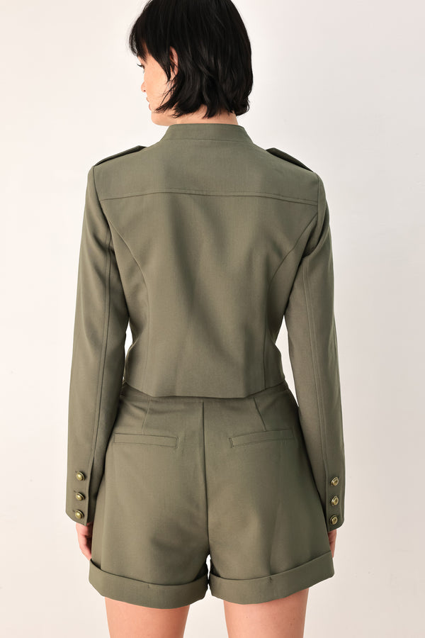 A model wearing an olive green military-style cropped jacket top with gold-tone double-breasted buttons, a front zipper, and a high mock neck | FREEMARKET