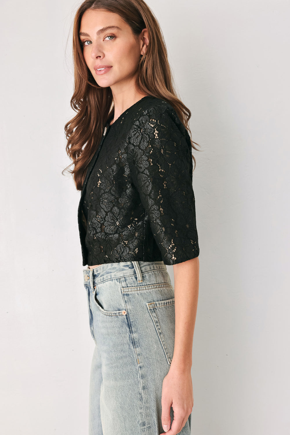 A woman wearing a black lace short-sleeve cropped top with a single button closure | FREEMARKET