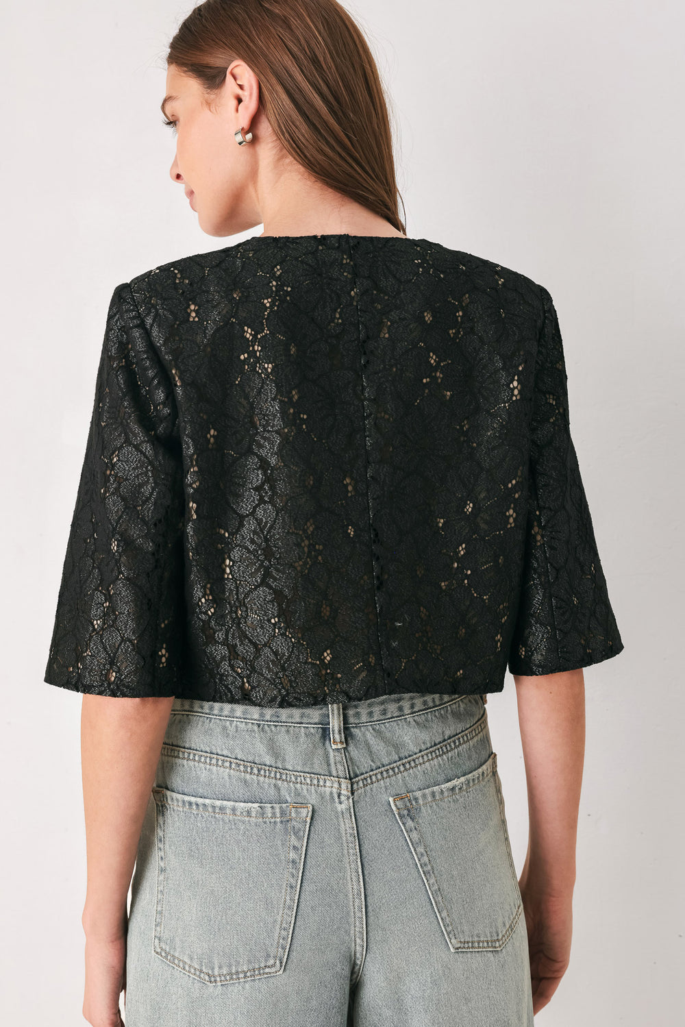 A woman wearing a black lace short-sleeve cropped top with a single button closure | FREEMARKET