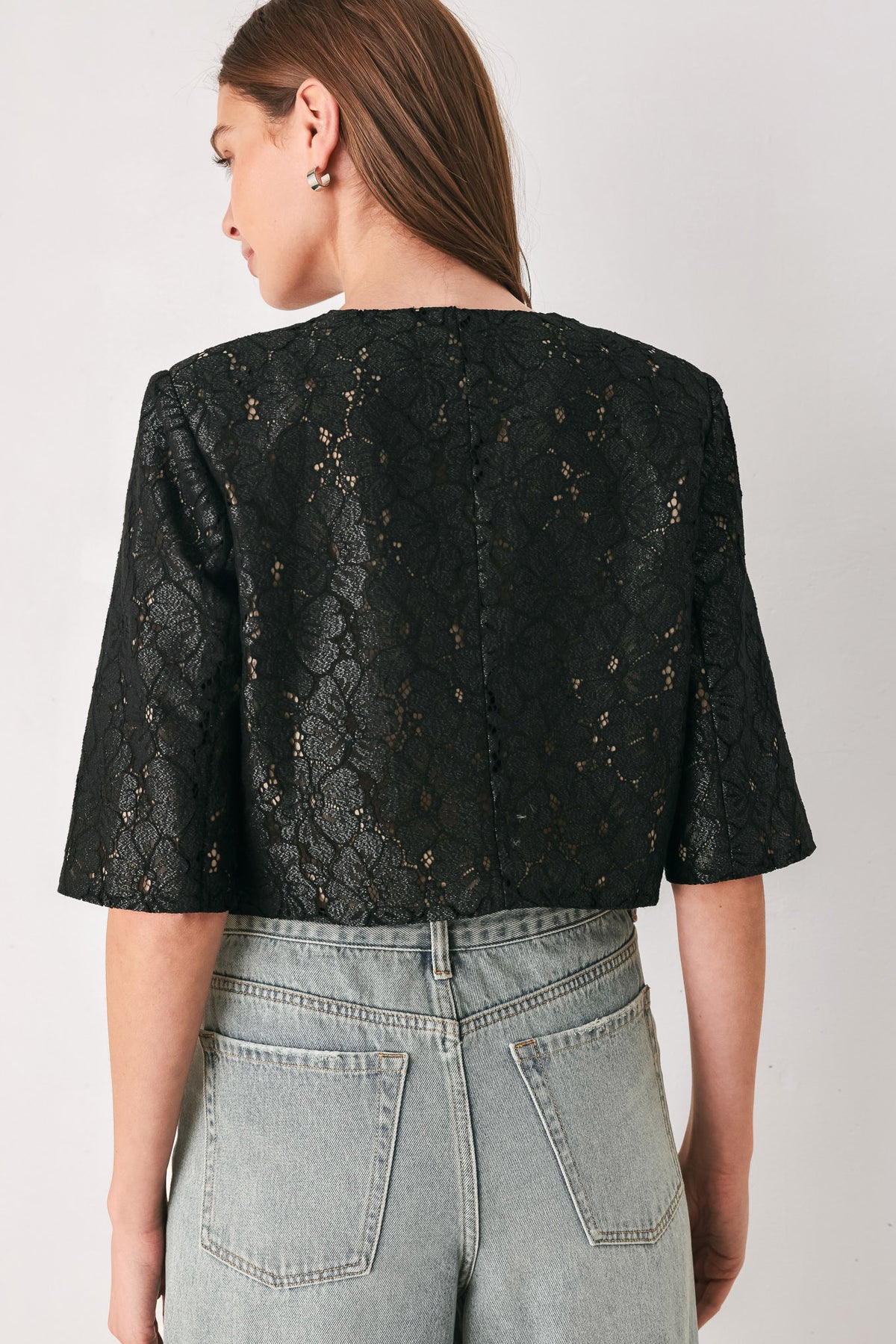 A woman wearing a black lace short-sleeve cropped top with a single button closure | FREEMARKET