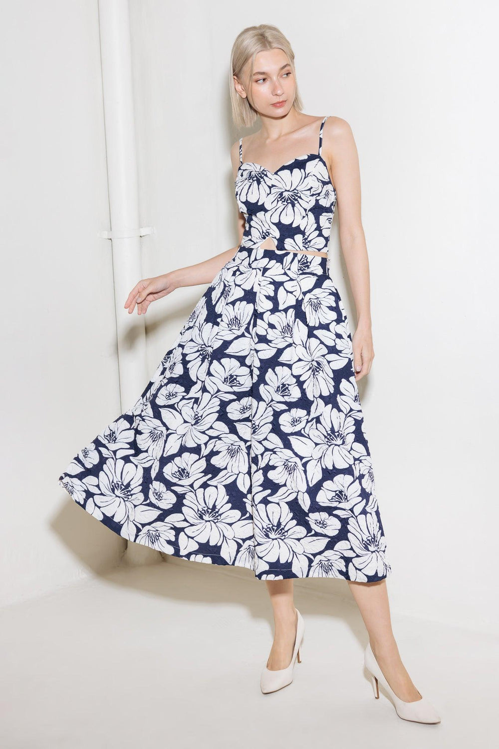 A navy woven midi skirt with a floral print, featuring inverted pleats, a side pocket, and a side zipper closure. Flying Tomato