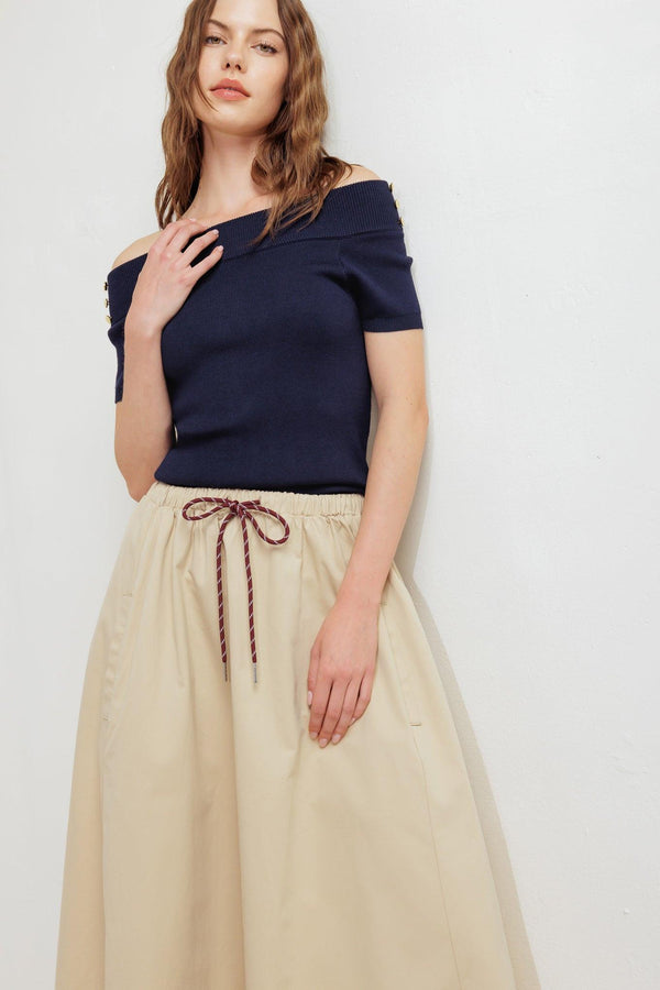 A solid woven midi skirt featuring elasticized waistband with contrasting front tie, side pockets and full skirt