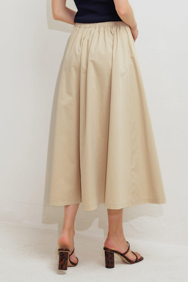A solid woven midi skirt featuring elasticized waistband with contrasting front tie, side pockets and full skirt