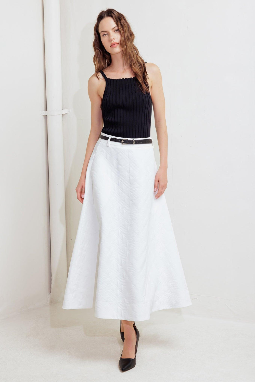 A white, textured woven midi skirt featuring a contrasting belt and back zipper closure