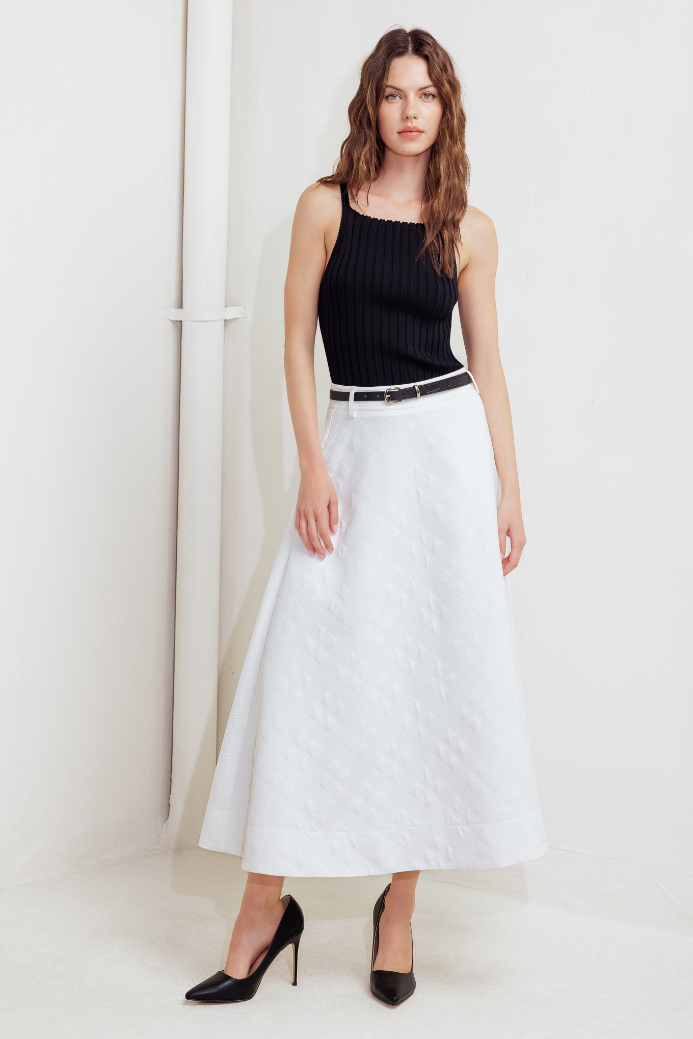A white, textured woven midi skirt featuring a contrasting belt and back zipper closure