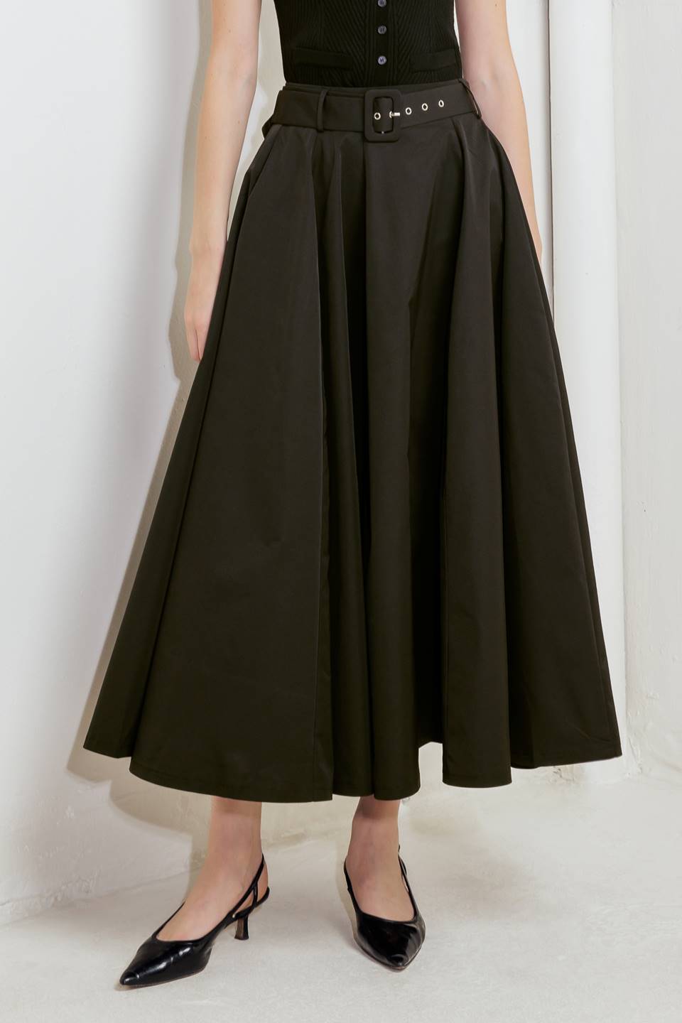 Woman wearing a black full midi skirt featuring self belt and side zipper closure | FREEMARKET