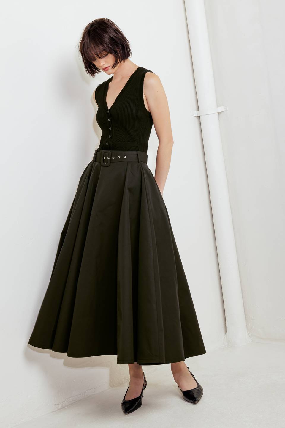 Woman wearing a black full midi skirt featuring self belt and side zipper closure | FREEMARKET