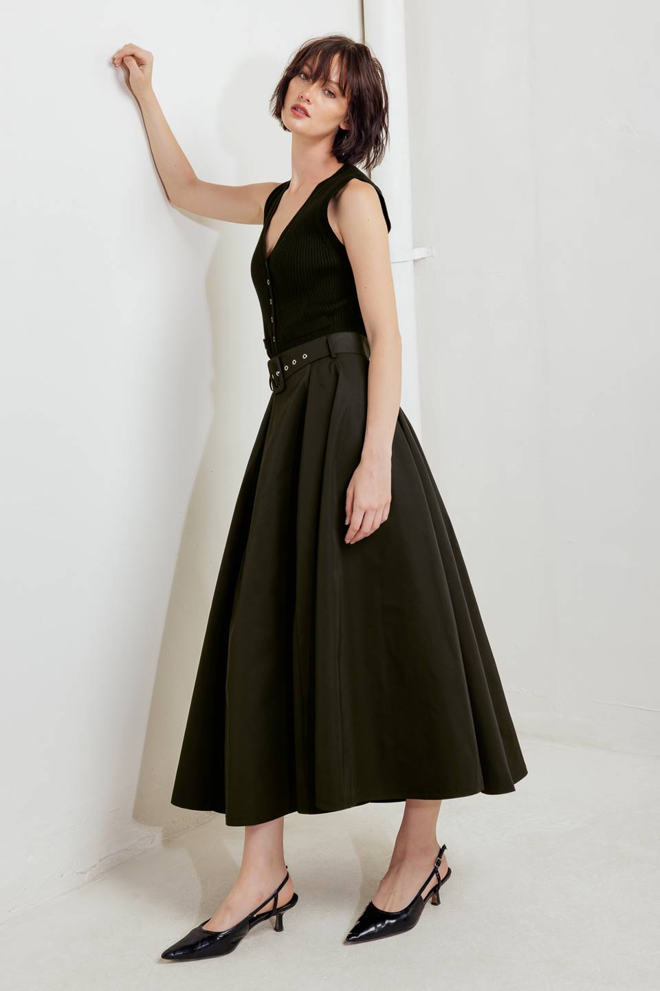 Woman wearing a black full midi skirt featuring self belt and side zipper closure | FREEMARKET
