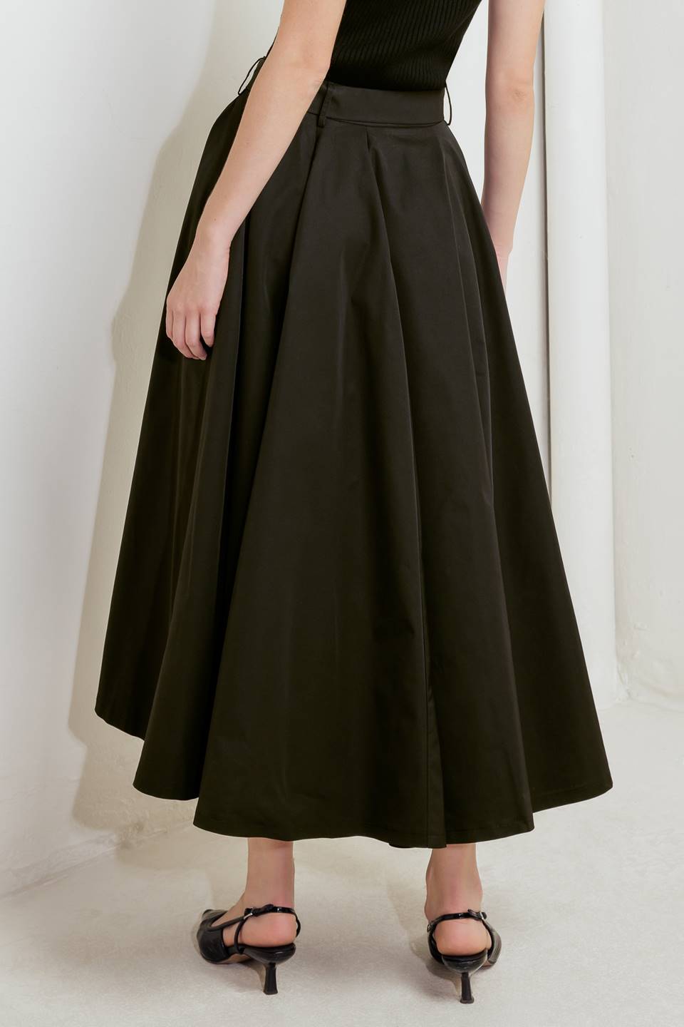 Woman wearing a black full midi skirt featuring self belt and side zipper closure | FREEMARKET