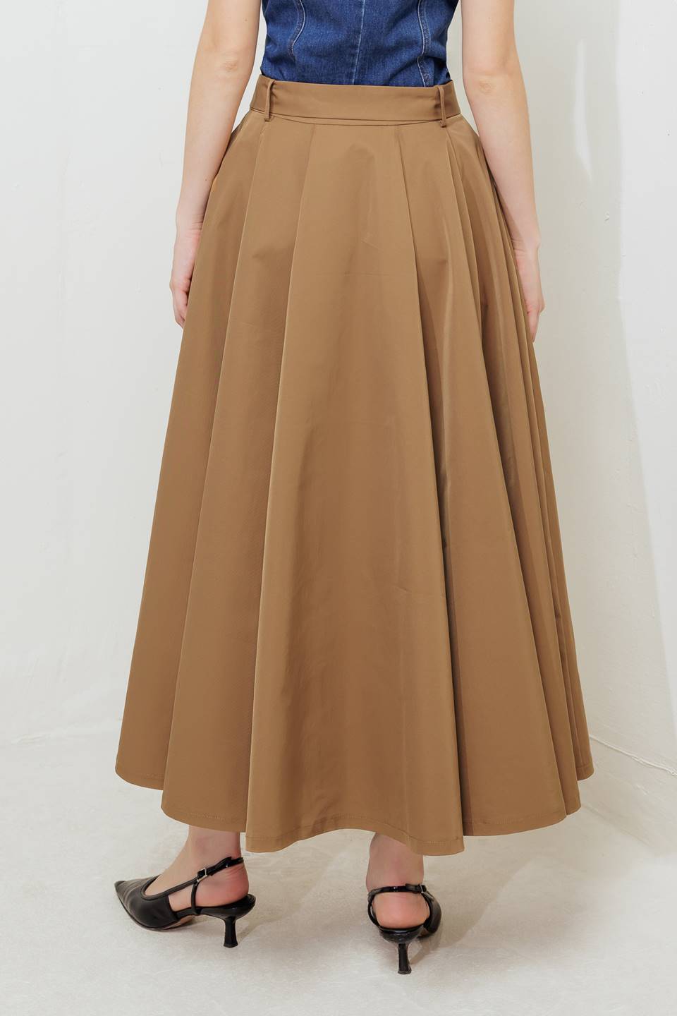 Woman wearing a camel full midi skirt featuring self belt and side zipper closure | FREEMARKET