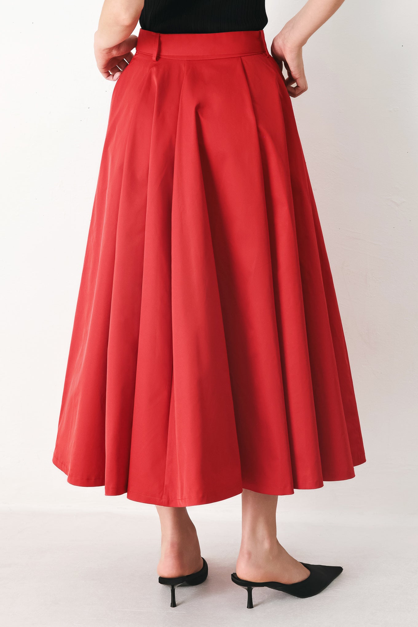 Woman wearing a red full midi skirt featuring self belt and side zipper closure | FREEMARKET