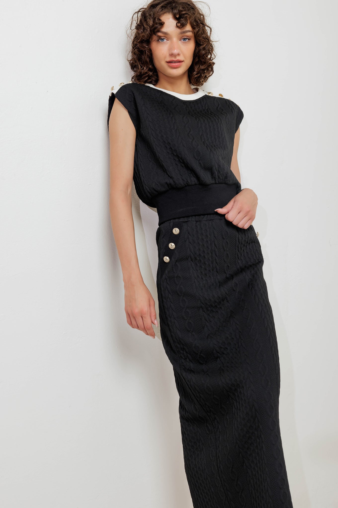 A knit midi skirt featuring elasticized waistband and side button detail. 