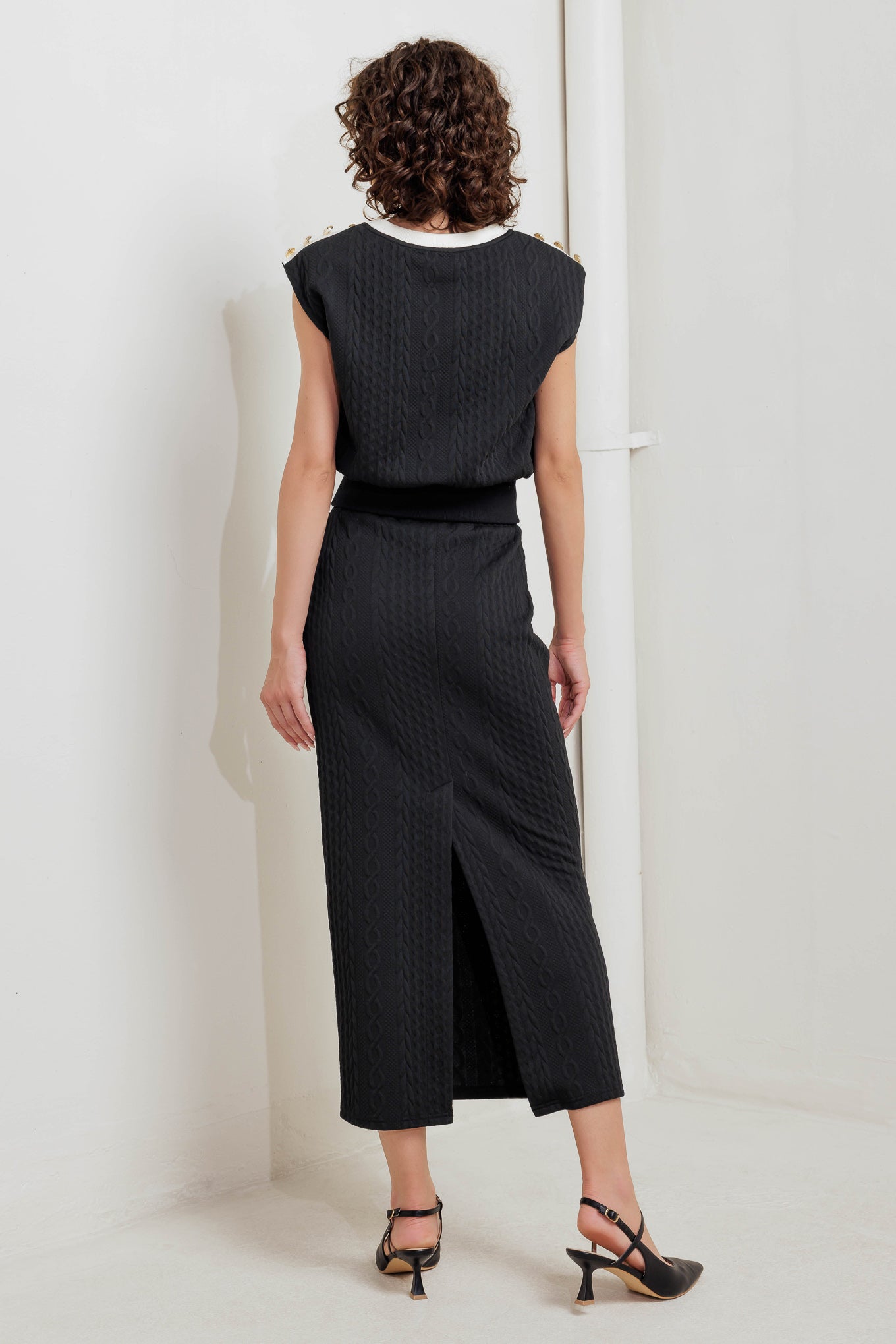 A knit midi skirt featuring elasticized waistband and side button detail. 