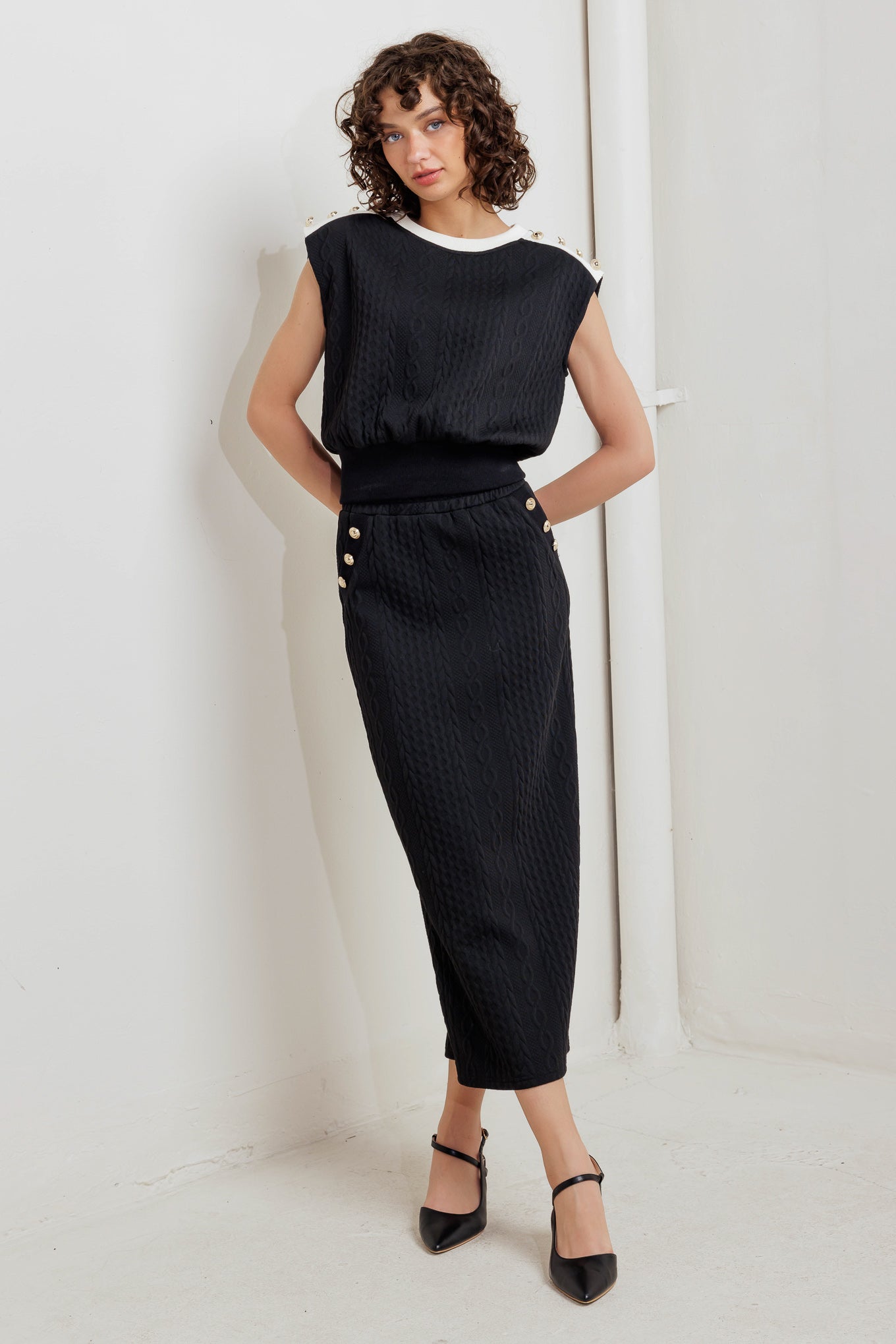 A knit midi skirt featuring elasticized waistband and side button detail. 