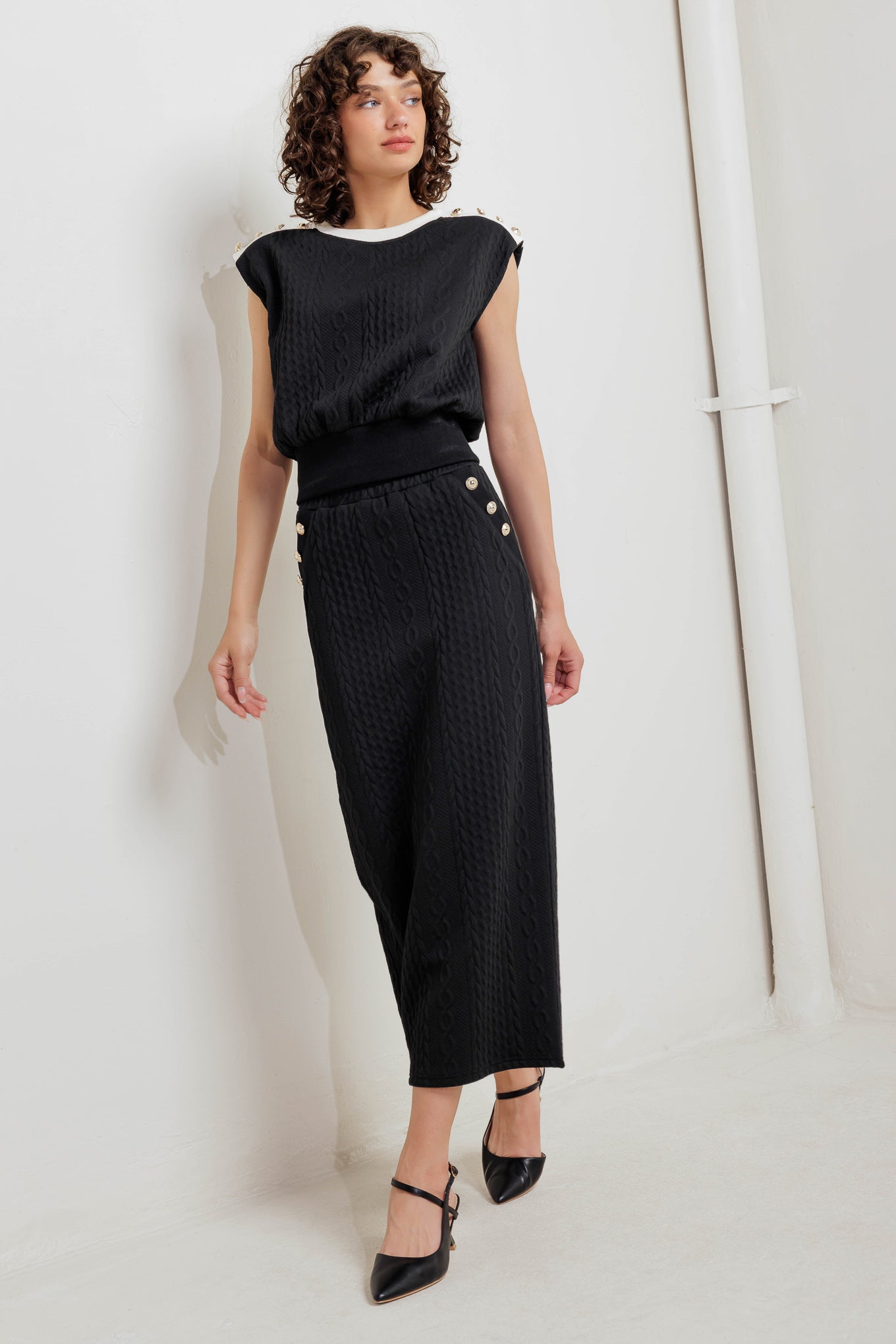 A knit midi skirt featuring elasticized waistband and side button detail. 