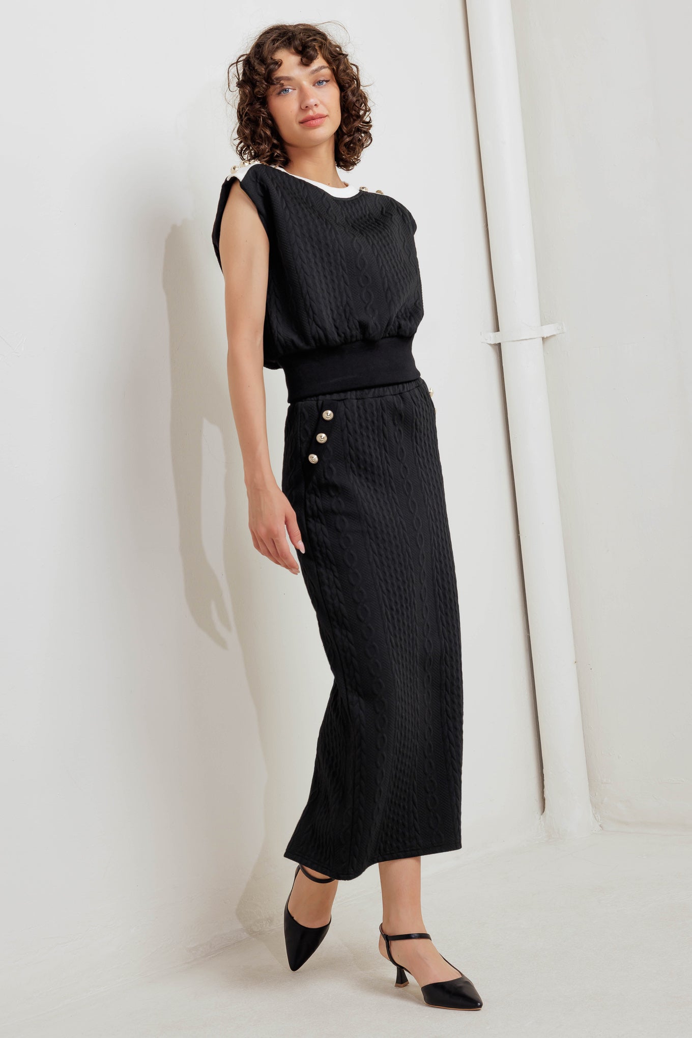 A knit midi skirt featuring elasticized waistband and side button detail. 