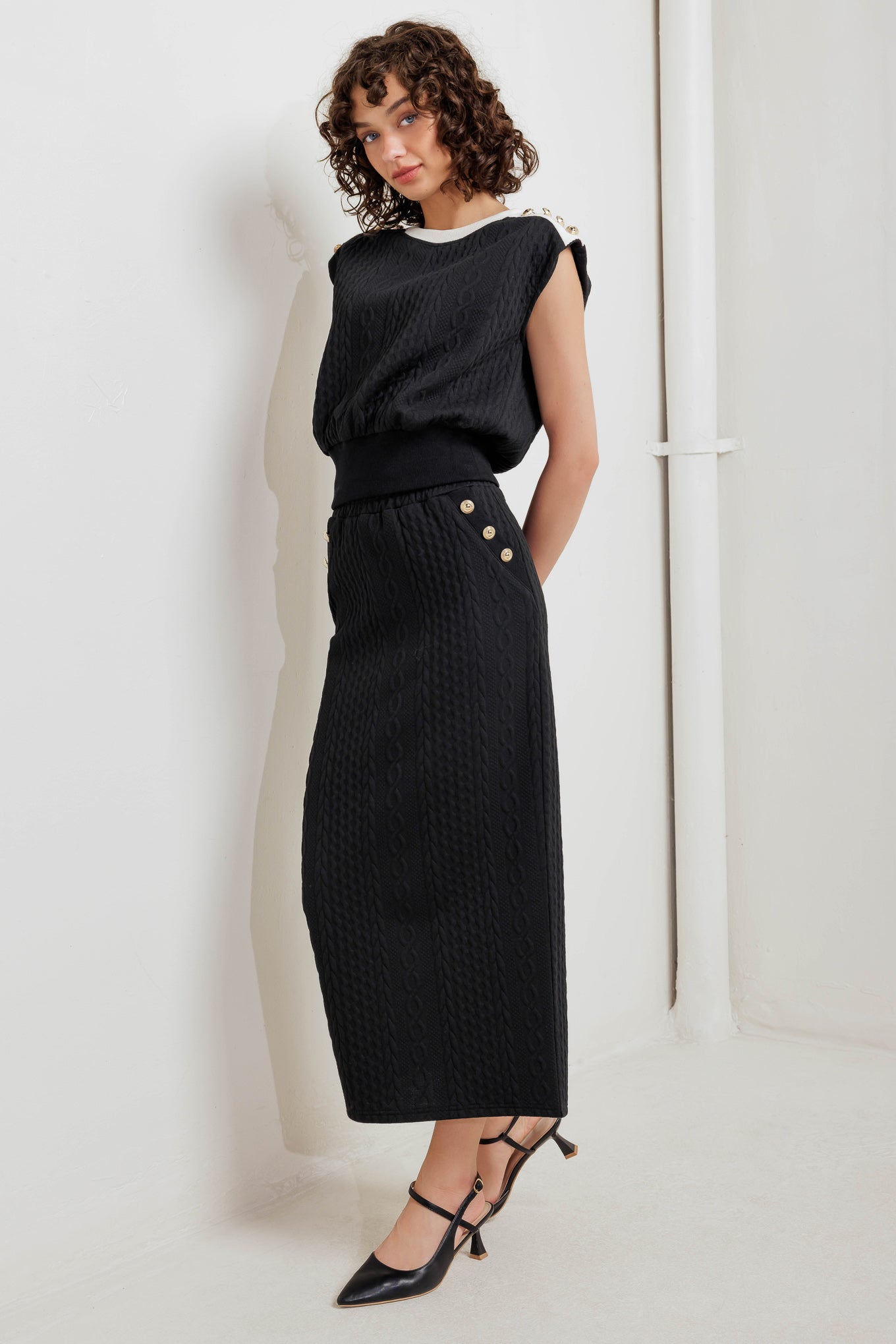 A knit midi skirt featuring elasticized waistband and side button detail. 