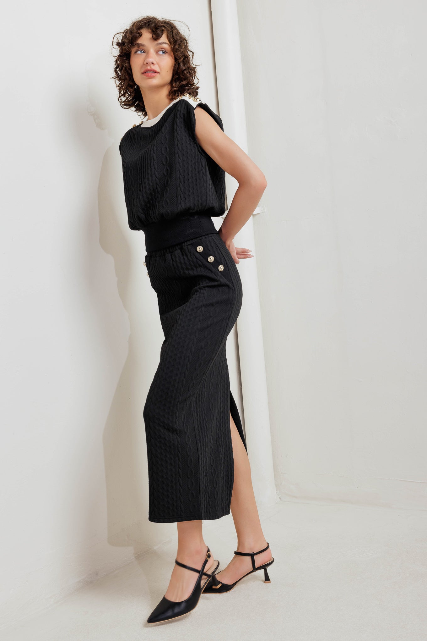 A knit midi skirt featuring elasticized waistband and side button detail. 
