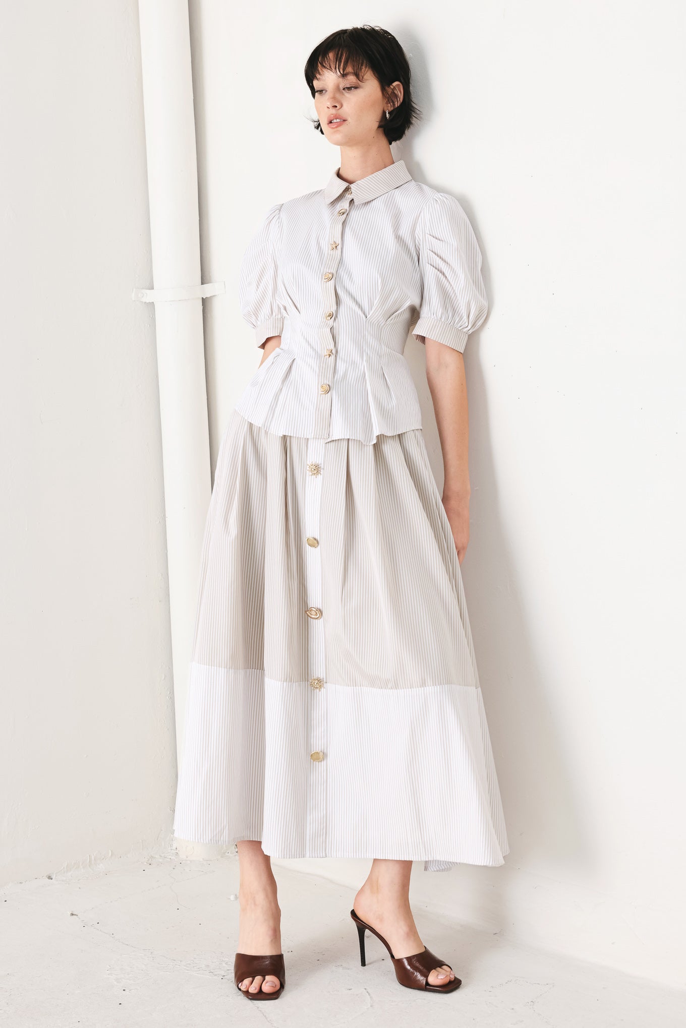 Woman wearing a taupe and white striped woven midi skirt with front button detail, box pleats and back zipper closure | FREEMARKET