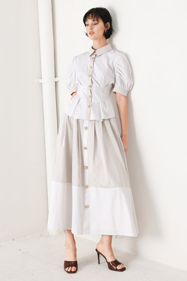 Woman wearing a taupe and white striped woven midi skirt with front button detail, box pleats and back zipper closure | FREEMARKET