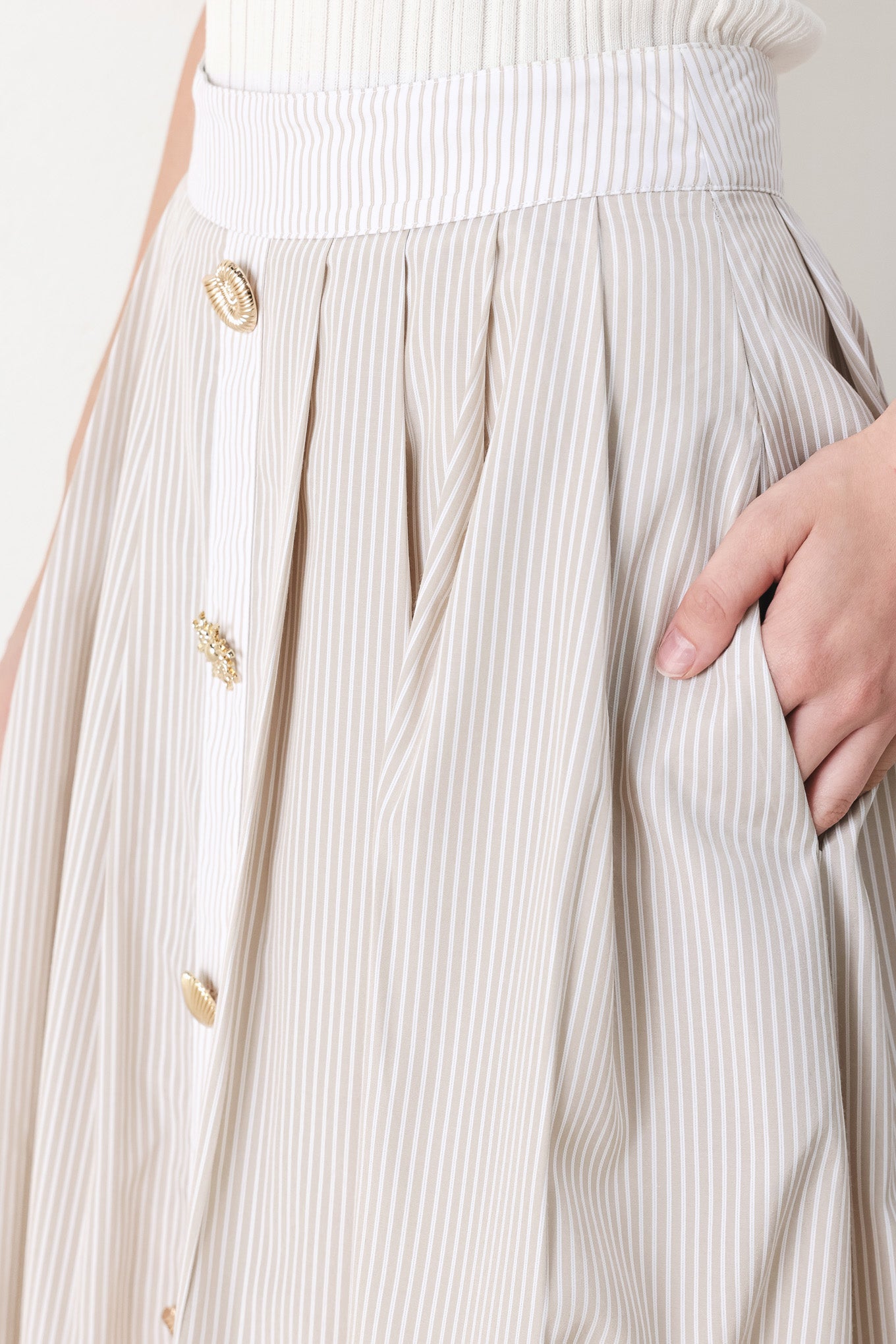 Woman wearing a taupe and white striped woven midi skirt with front button detail, box pleats and back zipper closure | FREEMARKET