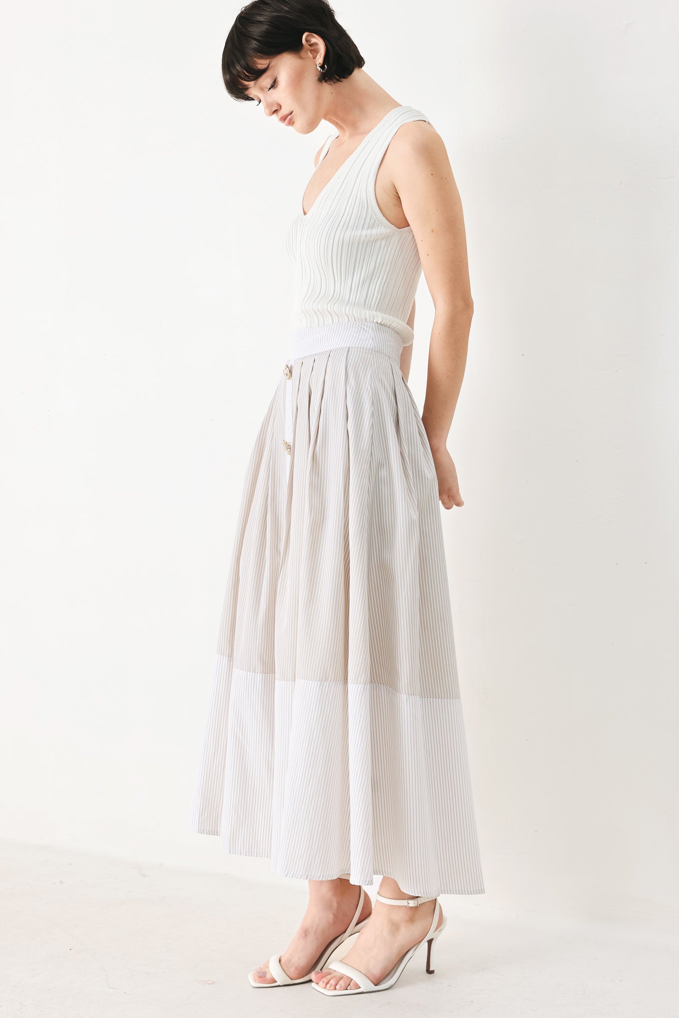 Woman wearing a taupe and white striped woven midi skirt with front button detail, box pleats and back zipper closure | FREEMARKET