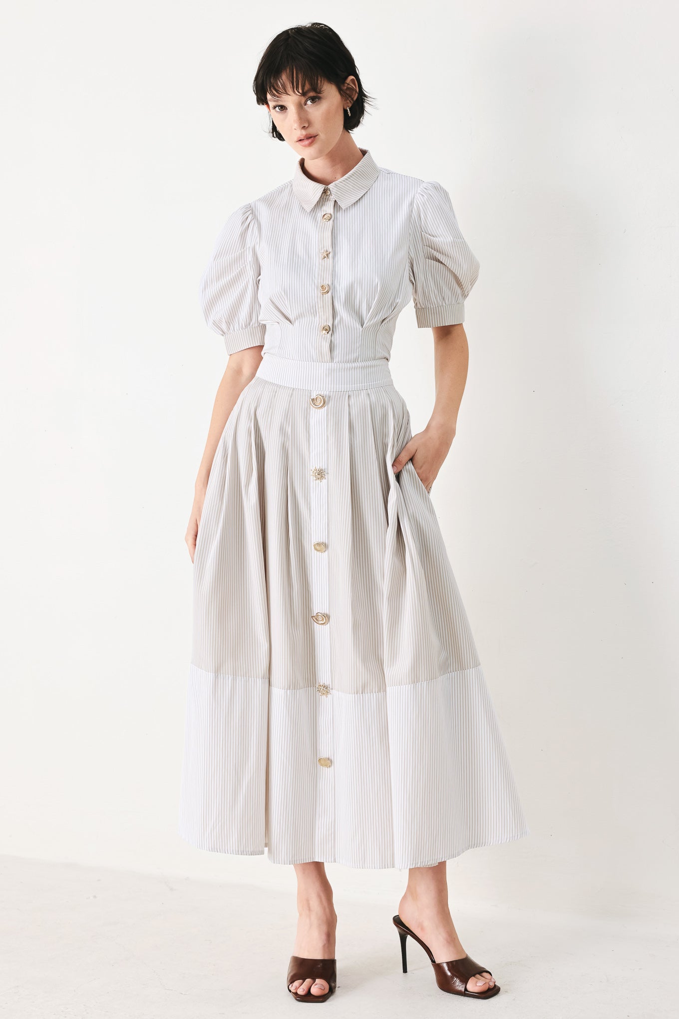 Woman wearing a taupe and white striped woven midi skirt with front button detail, box pleats and back zipper closure | FREEMARKET