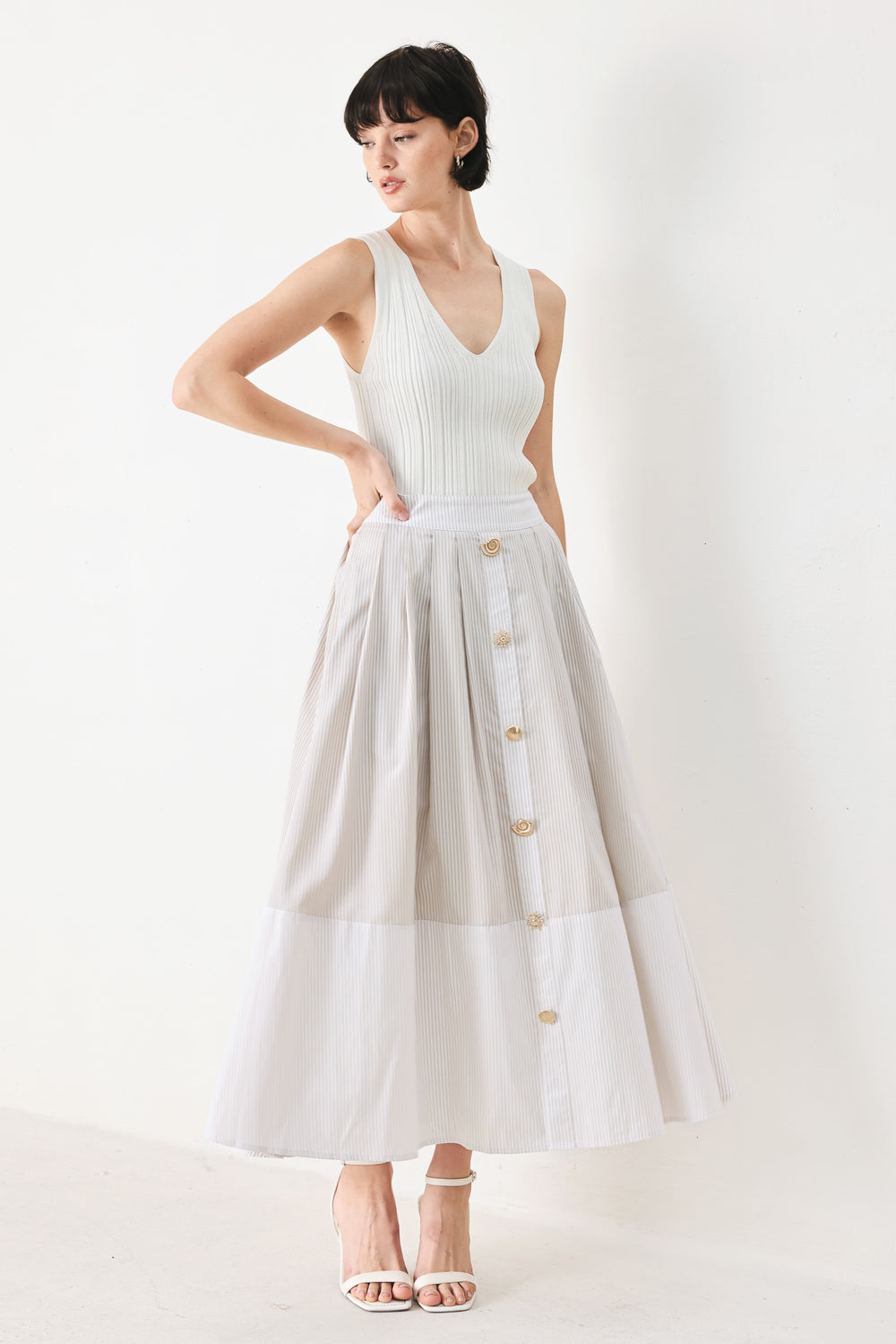 Woman wearing a taupe and white striped woven midi skirt with front button detail, box pleats and back zipper closure | FREEMARKET