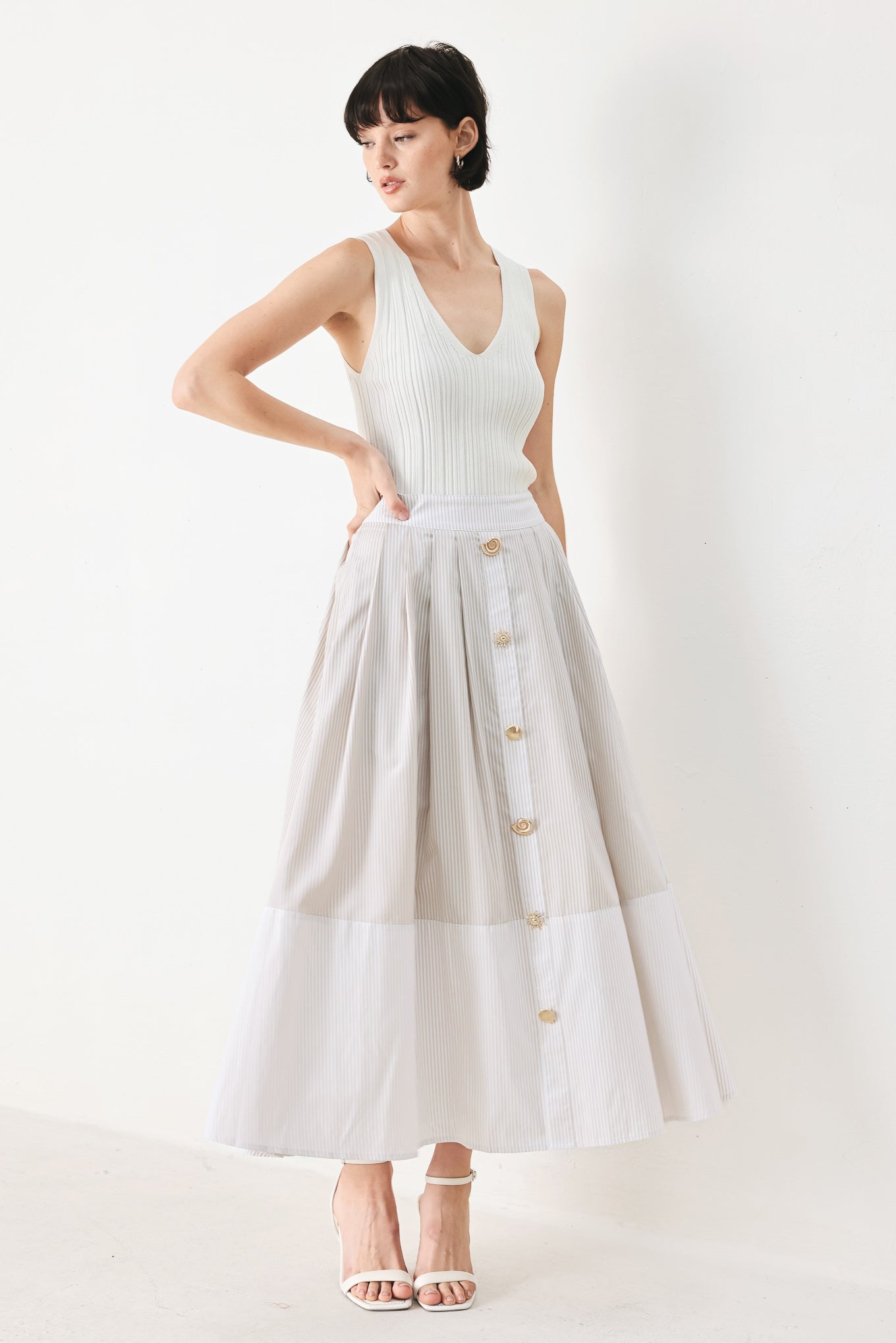 Woman wearing a taupe and white striped woven midi skirt with front button detail, box pleats and back zipper closure | FREEMARKET