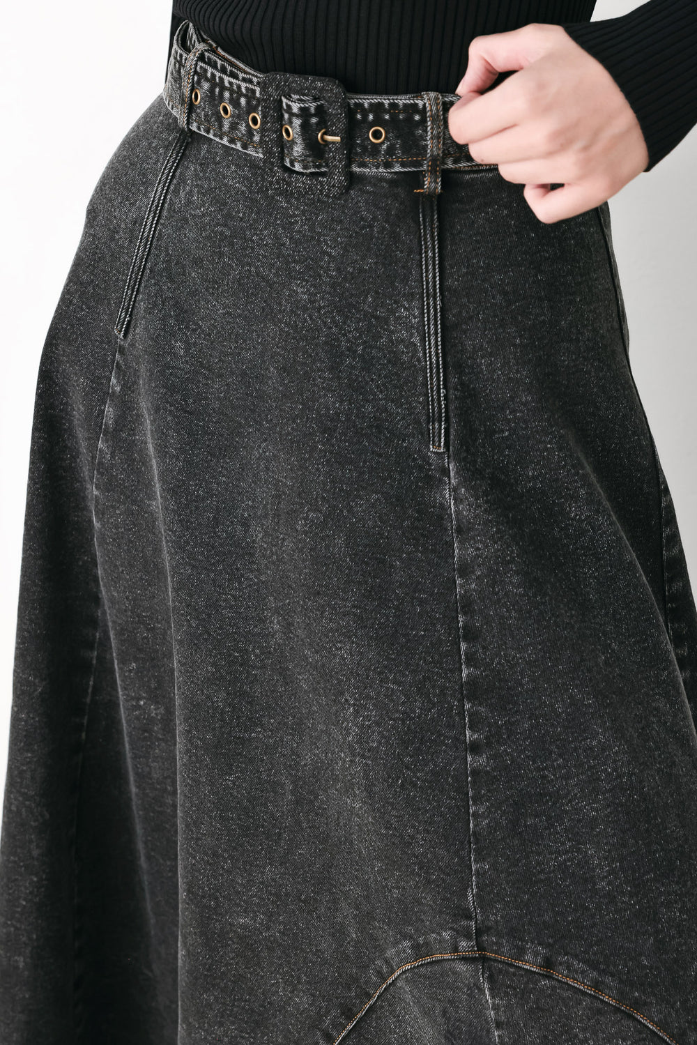 A model wearing a high-waisted, dark gray washed denim midi skirt with a decorative studded belt | FREEMARKET