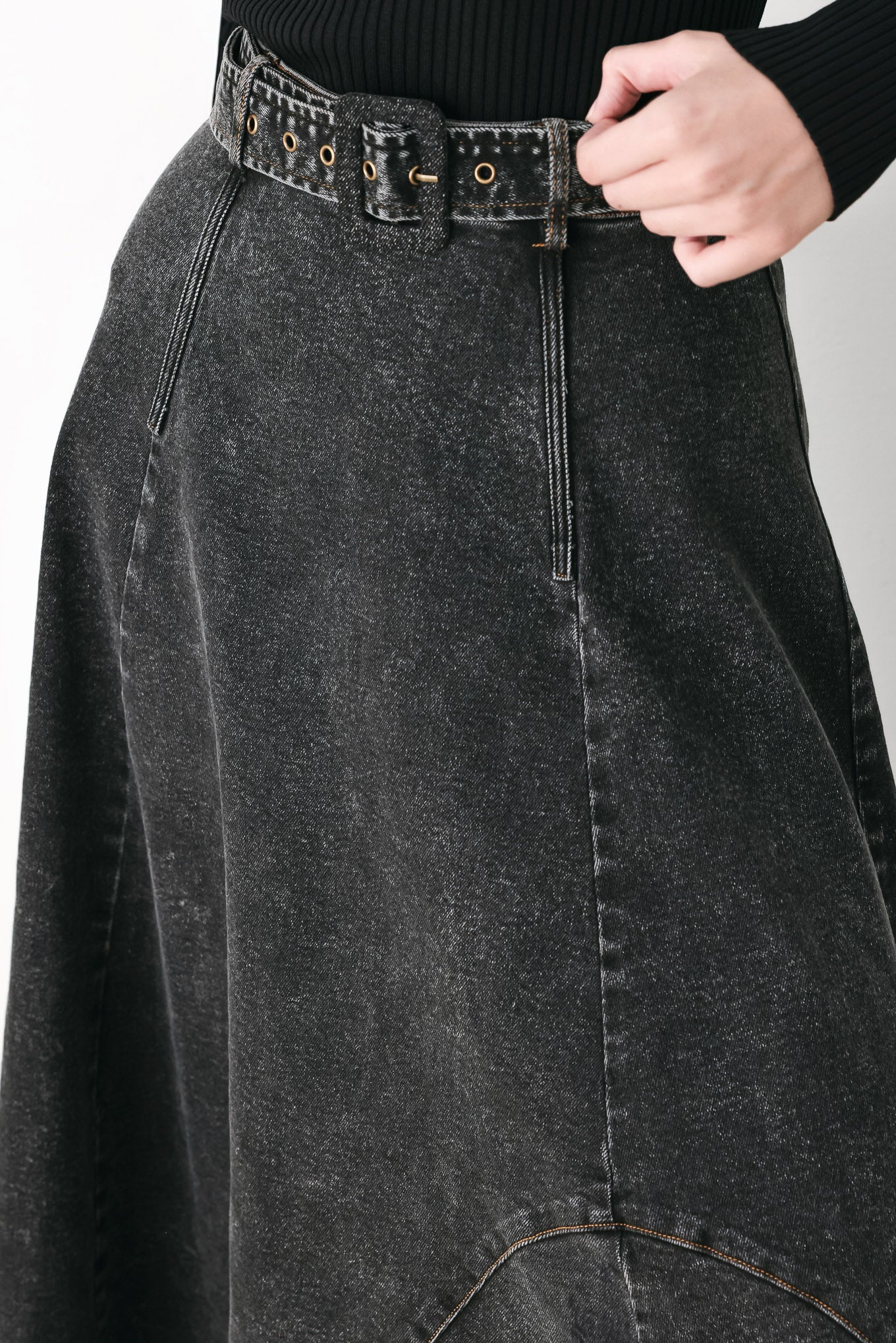A model wearing a high-waisted, dark gray washed denim midi skirt with a decorative studded belt | FREEMARKET
