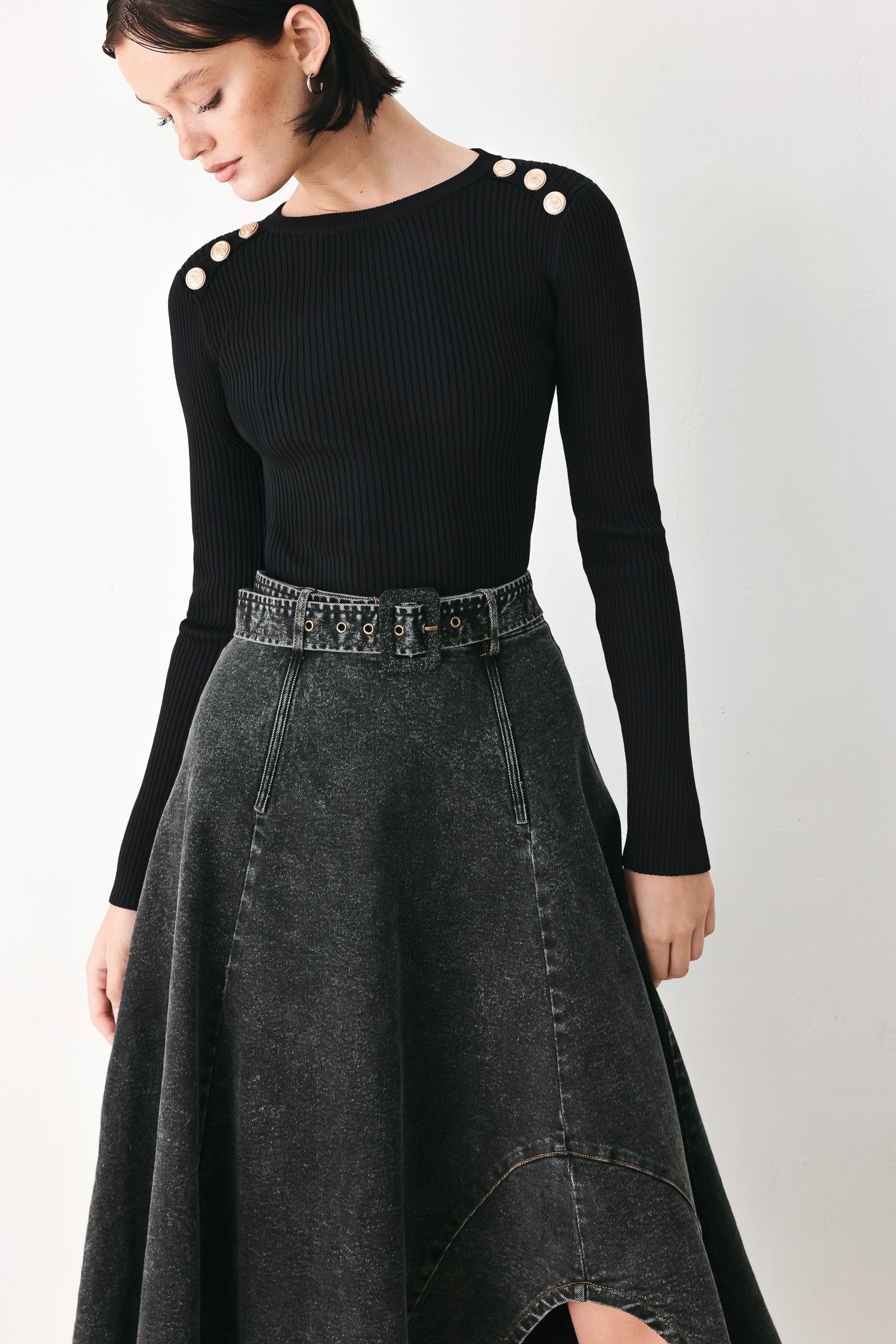 A model wearing a high-waisted, dark gray washed denim midi skirt with a decorative studded belt | FREEMARKET