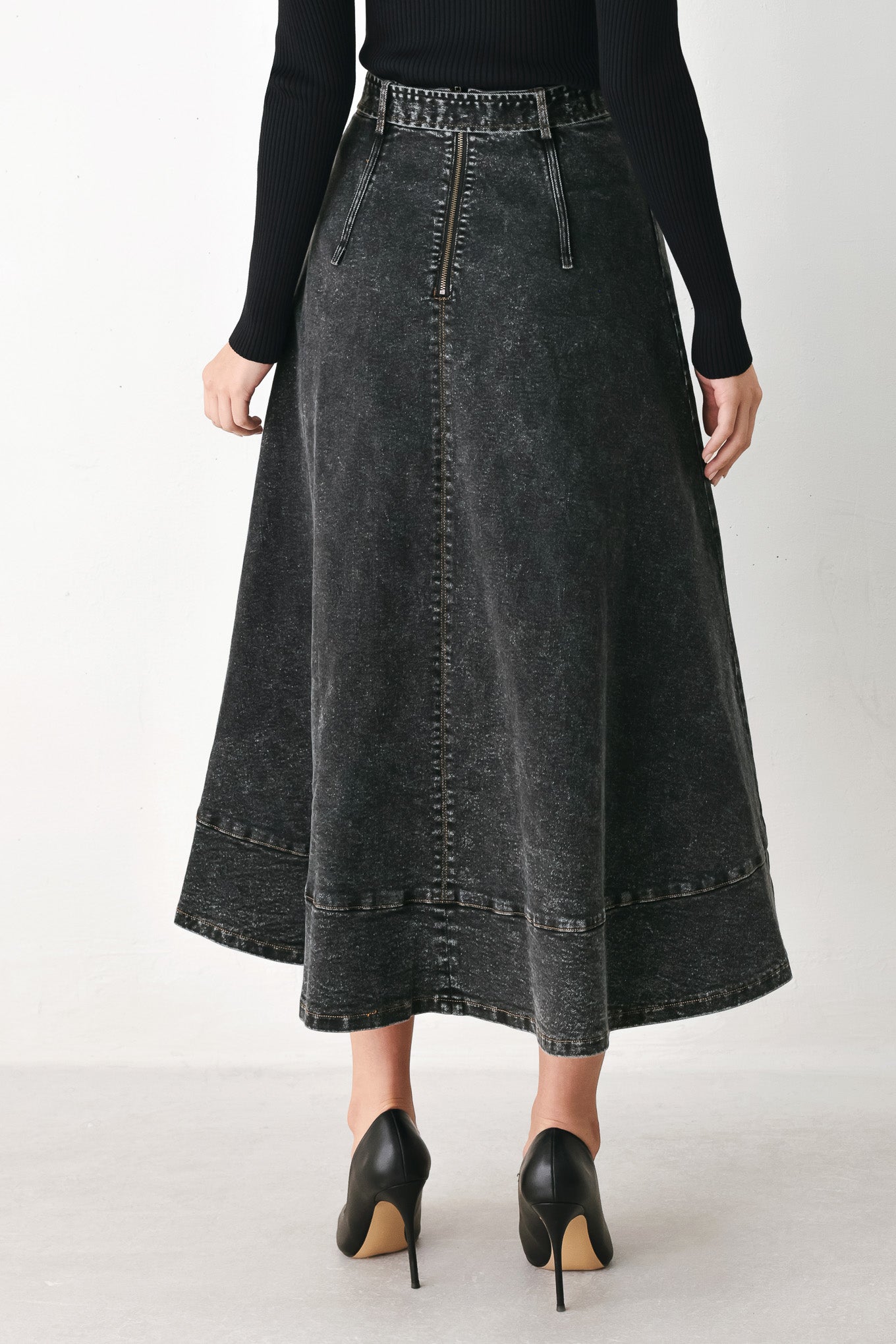A model wearing a high-waisted, dark gray washed denim midi skirt with a decorative studded belt | FREEMARKET