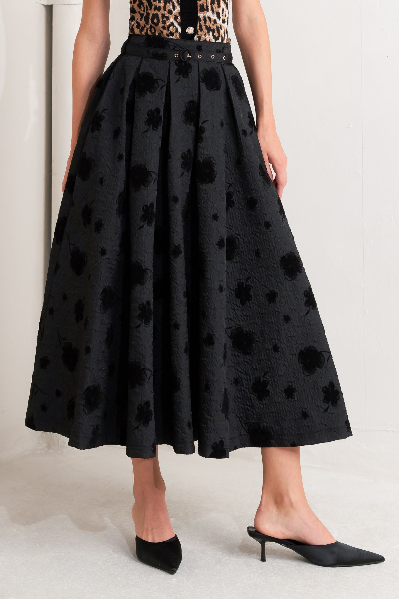 A textured woven full midi skirt with self belt and back zipper closure.