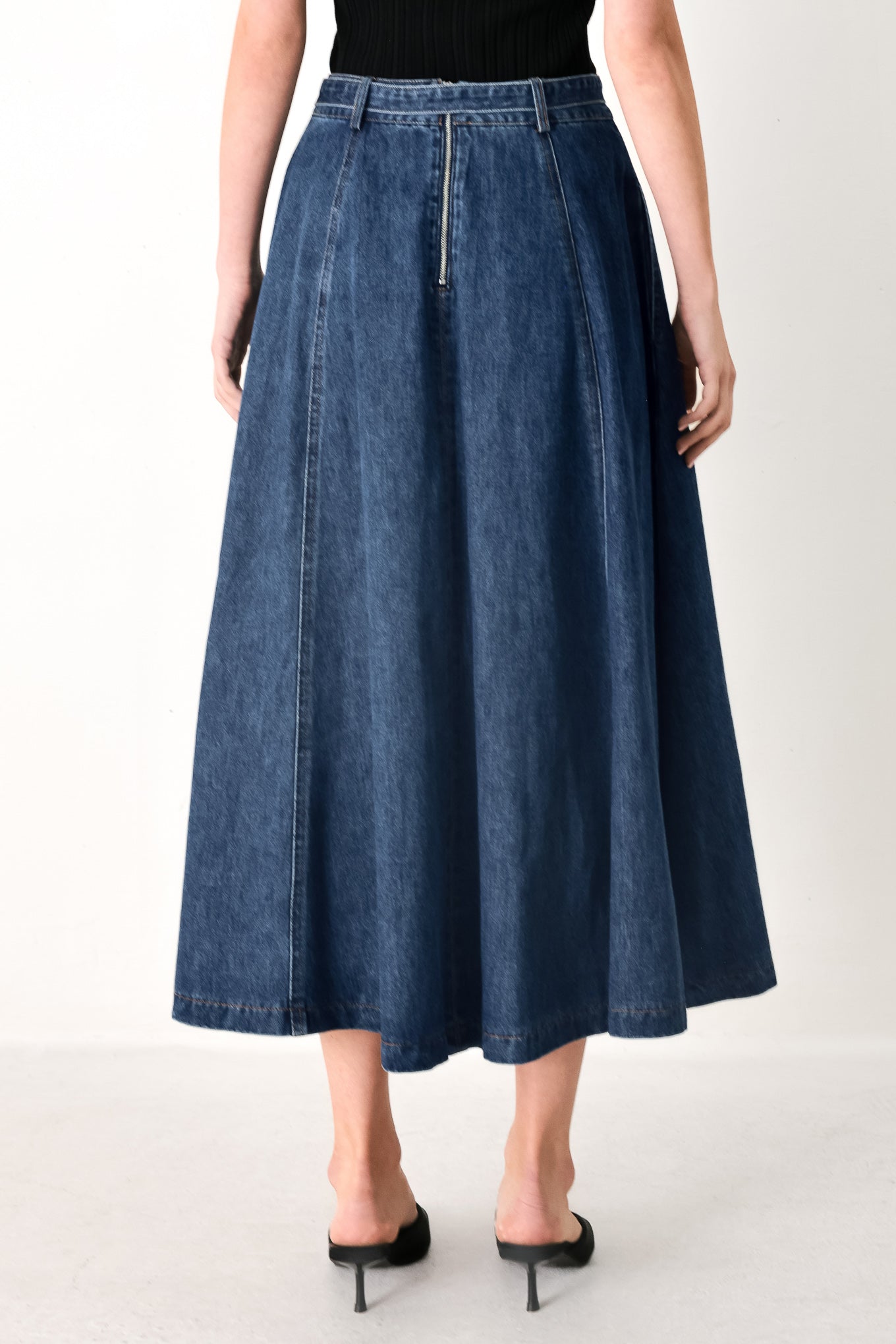 Woman wearing a blue denim circle midi skirt featuring self belt, button down detail and back zipper closure | FREEMARKET