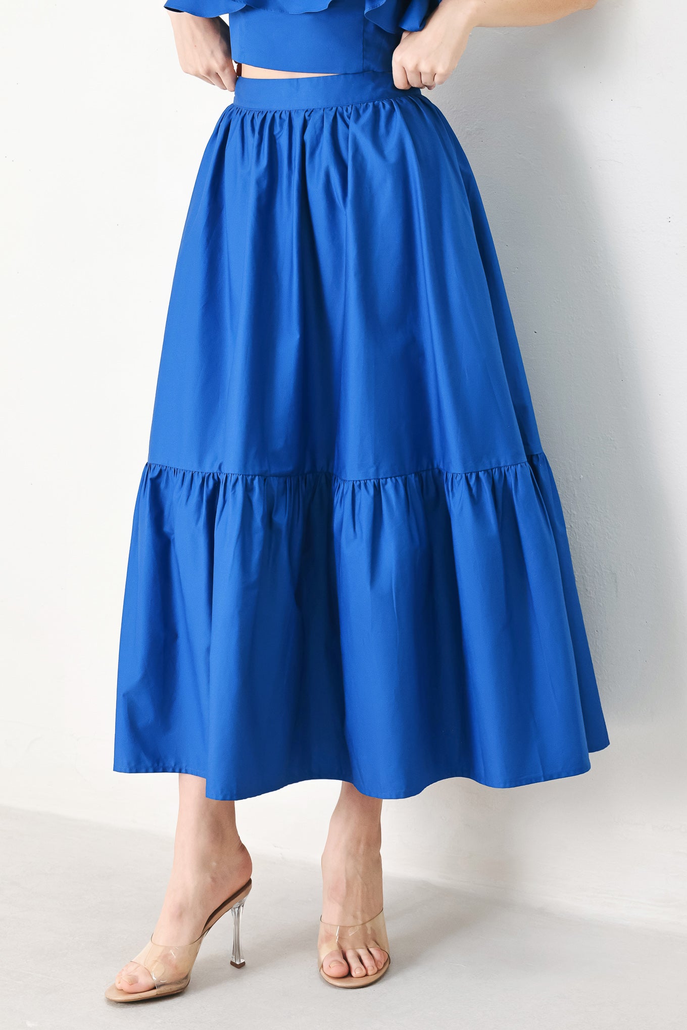 A solid woven midi skirt with ruffle hem and back zipper closure.