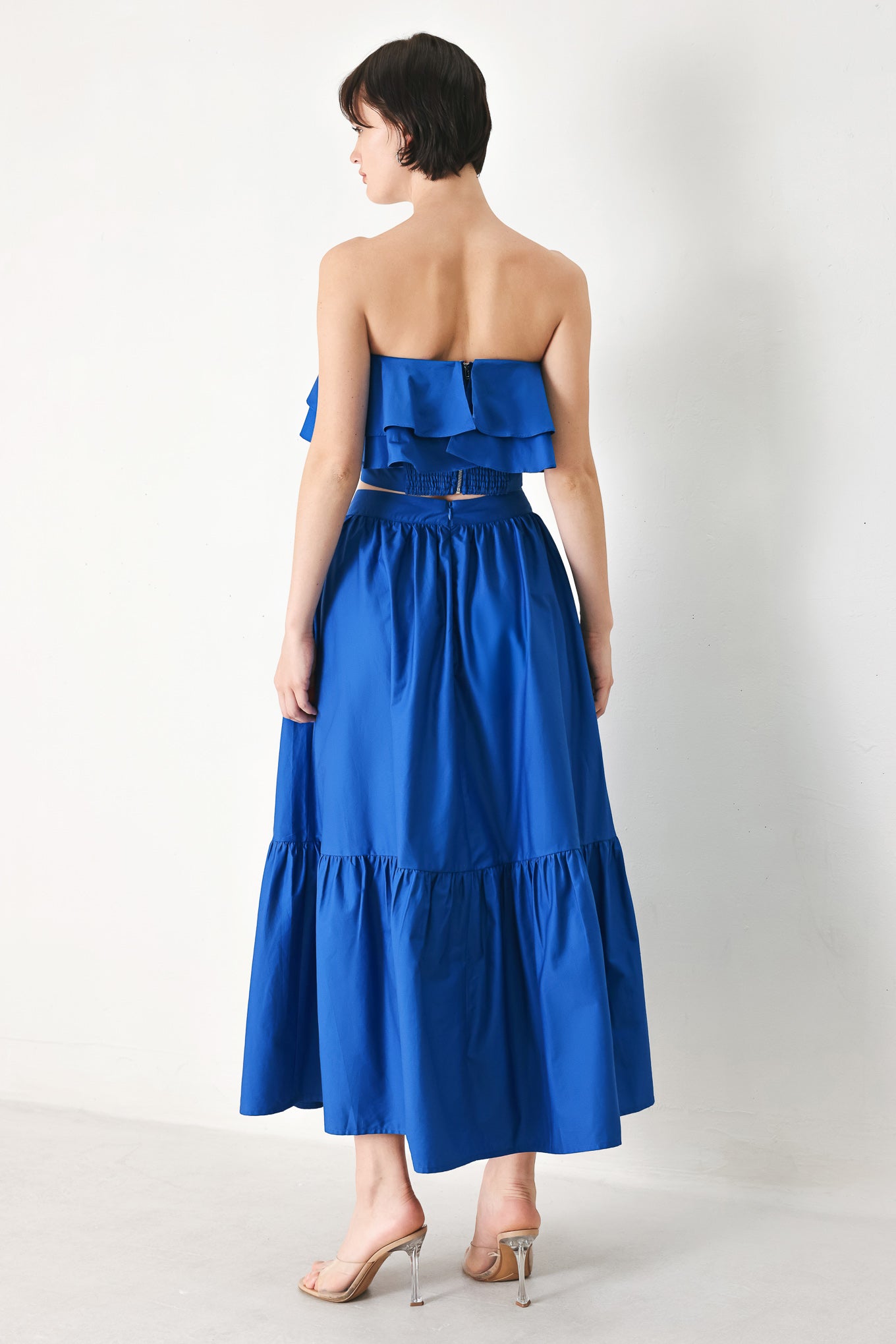 A solid woven midi skirt with ruffle hem and back zipper closure.