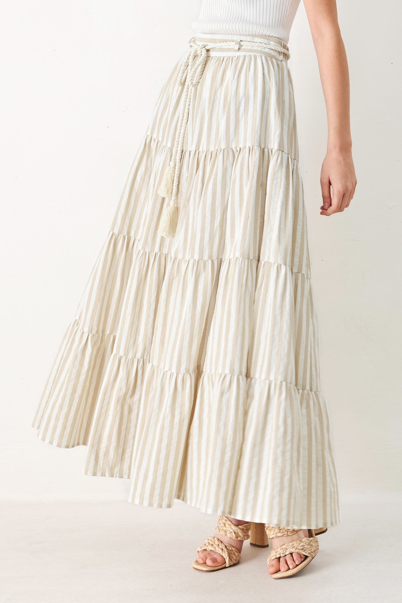 Woman wearing a long, tiered taupe and white striped maxi skirt with rope belt and elastic back waistband | FREEMARKET