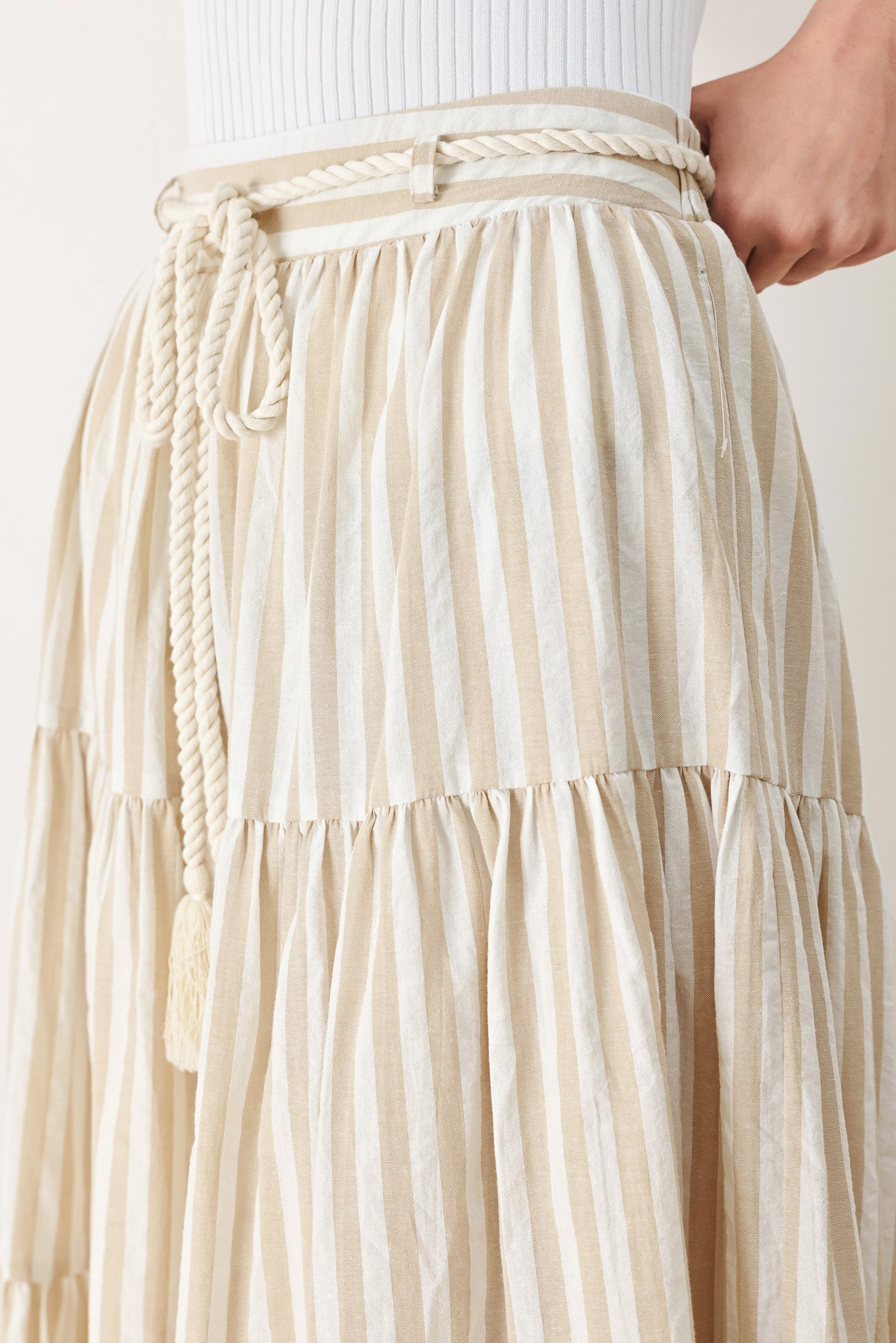 Woman wearing a long, tiered taupe and white striped maxi skirt with rope belt and elastic back waistband | FREEMARKET