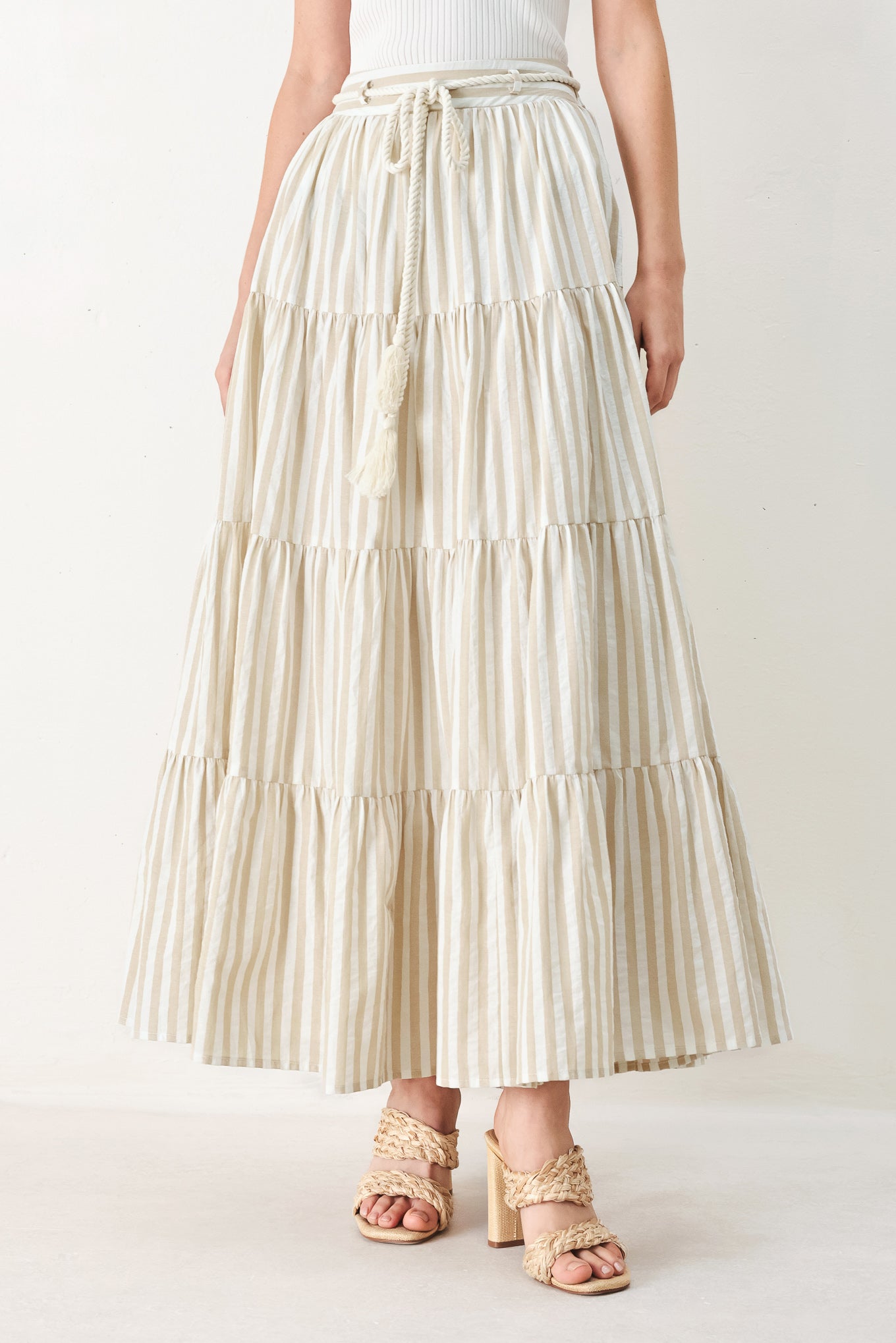 Woman wearing a long, tiered taupe and white striped maxi skirt with rope belt and elastic back waistband | FREEMARKET