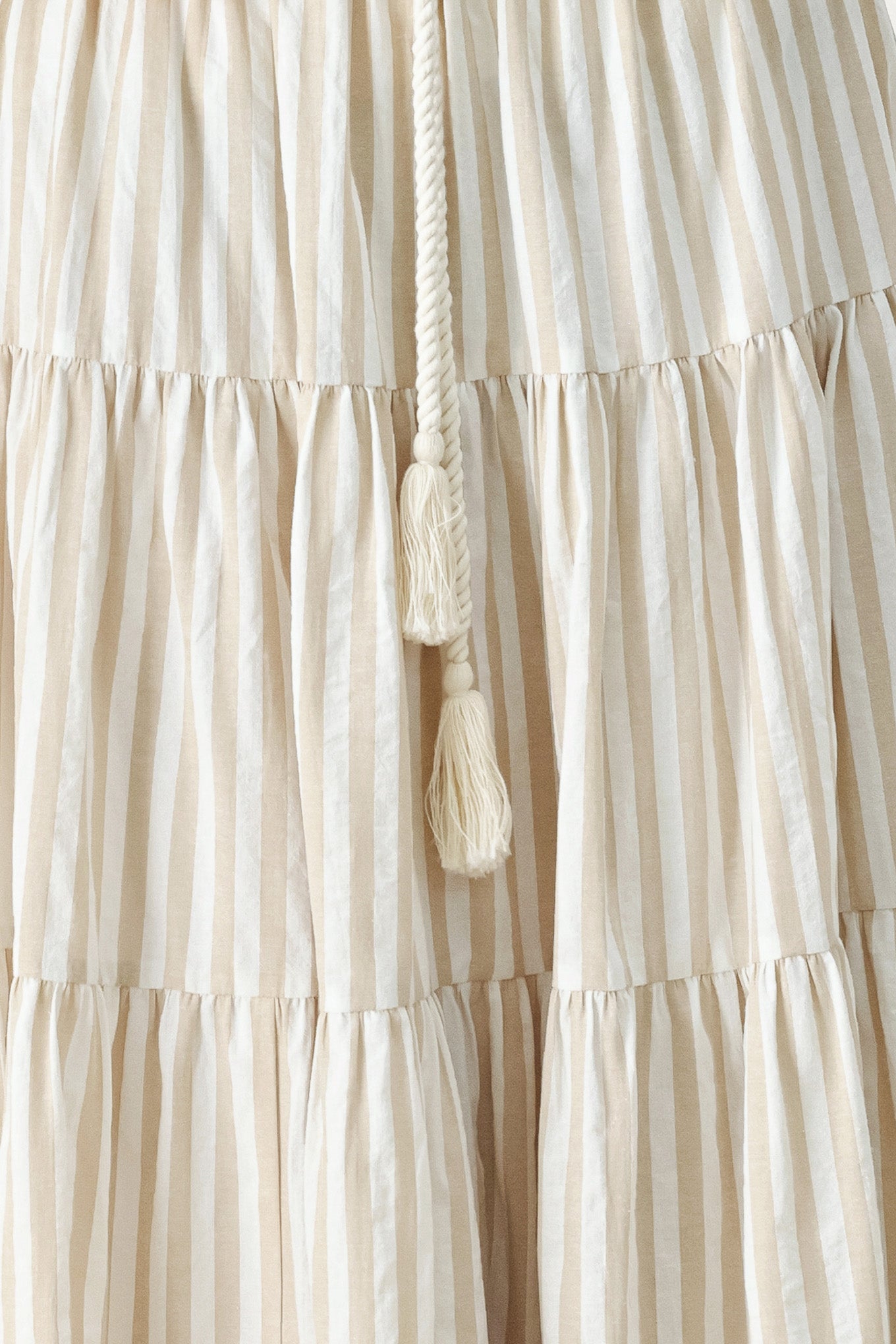 Woman wearing a long, tiered taupe and white striped maxi skirt with rope belt and elastic back waistband | FREEMARKET