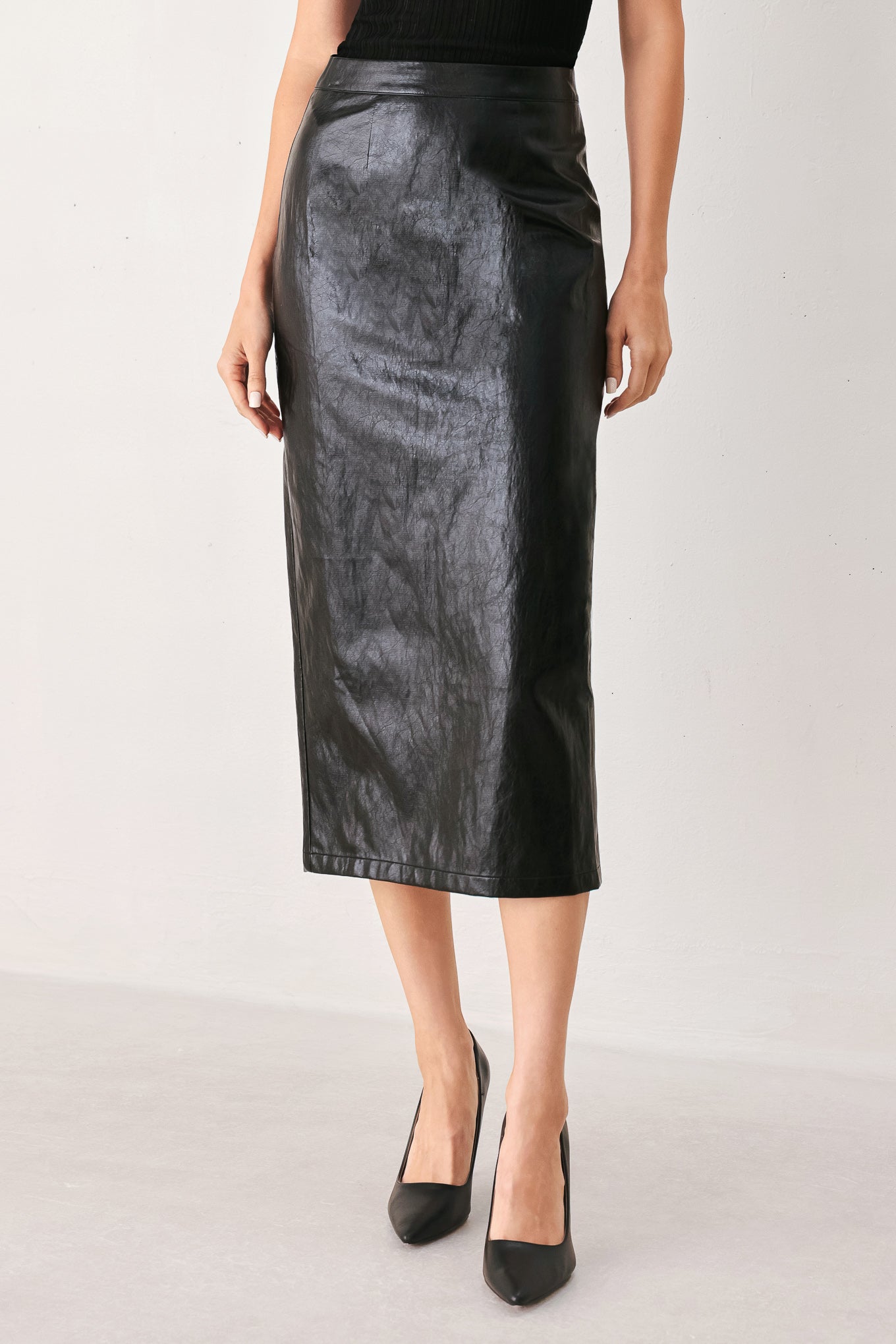 A woman wearing a black faux-leather midi skirt | FREEMAKRET
