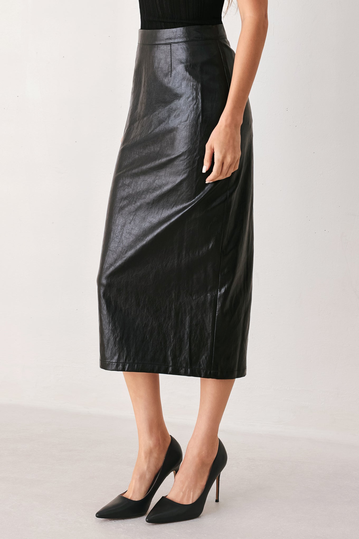 A woman wearing a black faux-leather midi skirt | FREEMAKRET