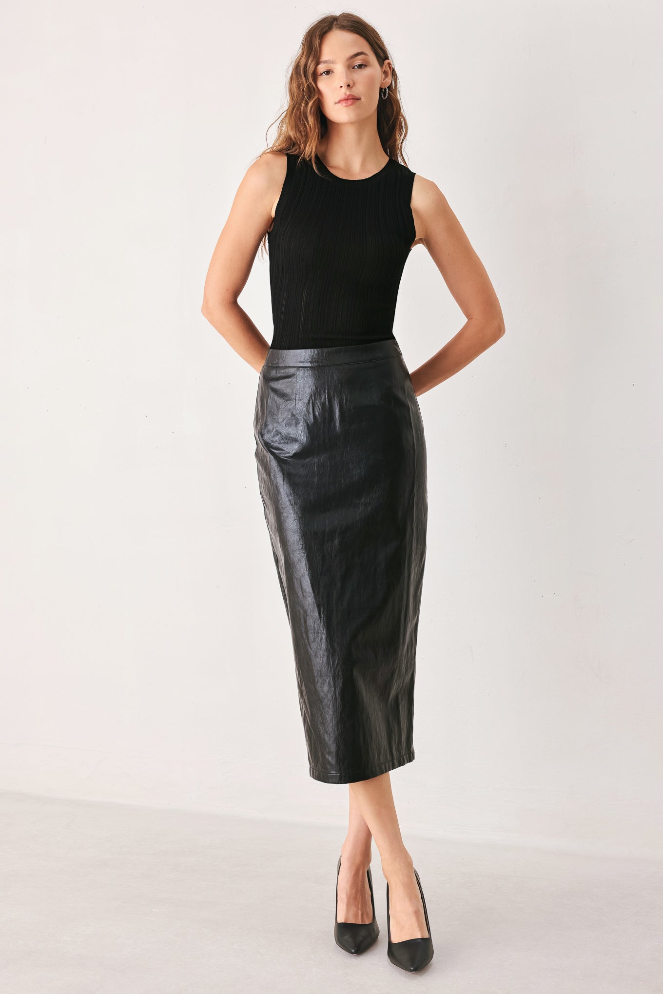 A woman wearing a black faux-leather midi skirt | FREEMAKRET