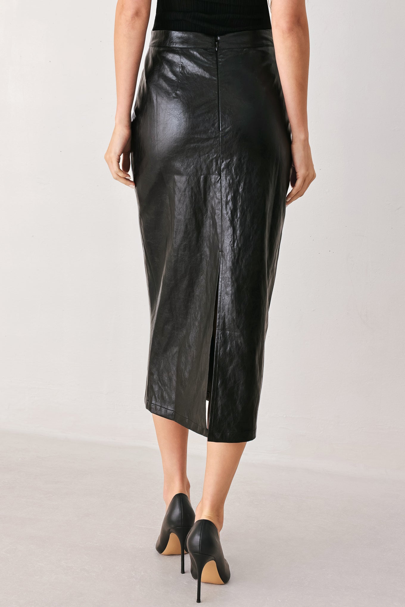 A woman wearing a black faux-leather midi skirt | FREEMAKRET