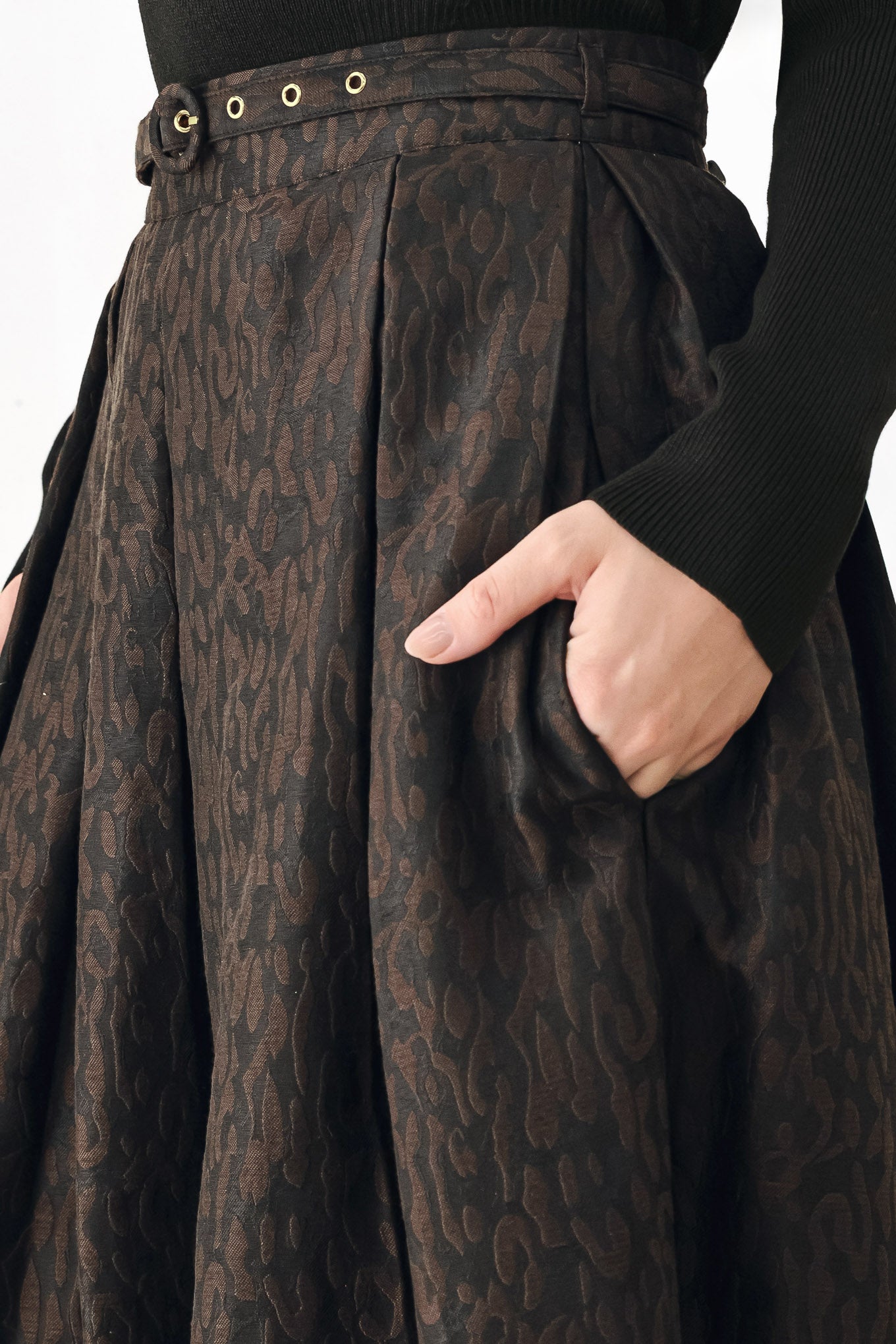 A high-waisted, pleated midi skirt in a dark brown and black jacquard leopard print pattern, styled with a matching belt  | FREEMARKET