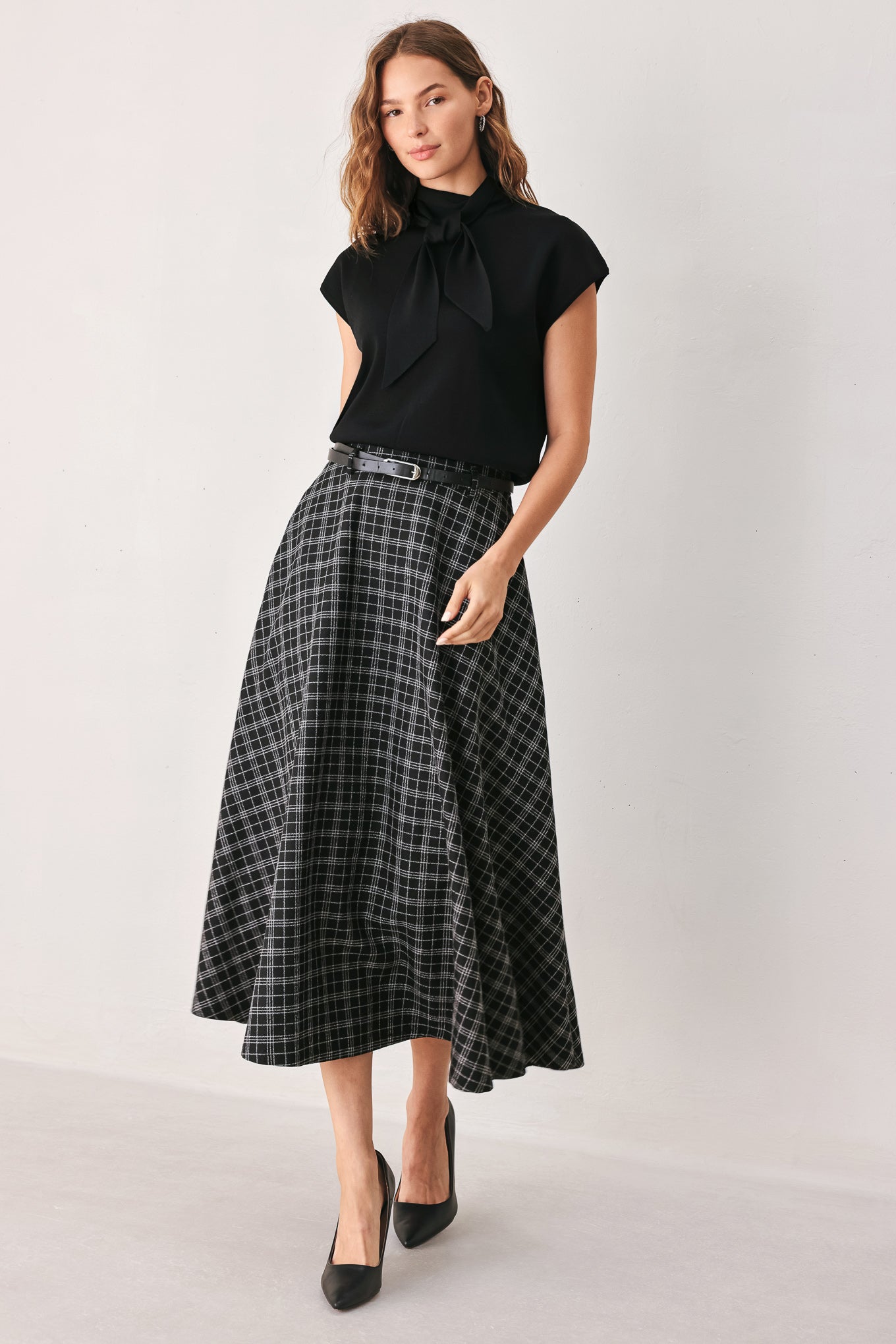 A woman wearing a black and gray plaid midi skirt with a black belt | FREEMARKET