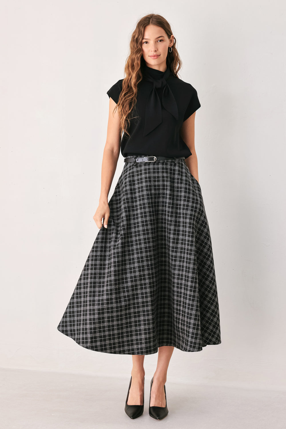 A woman wearing a black and gray plaid midi skirt with a black belt | FREEMARKET