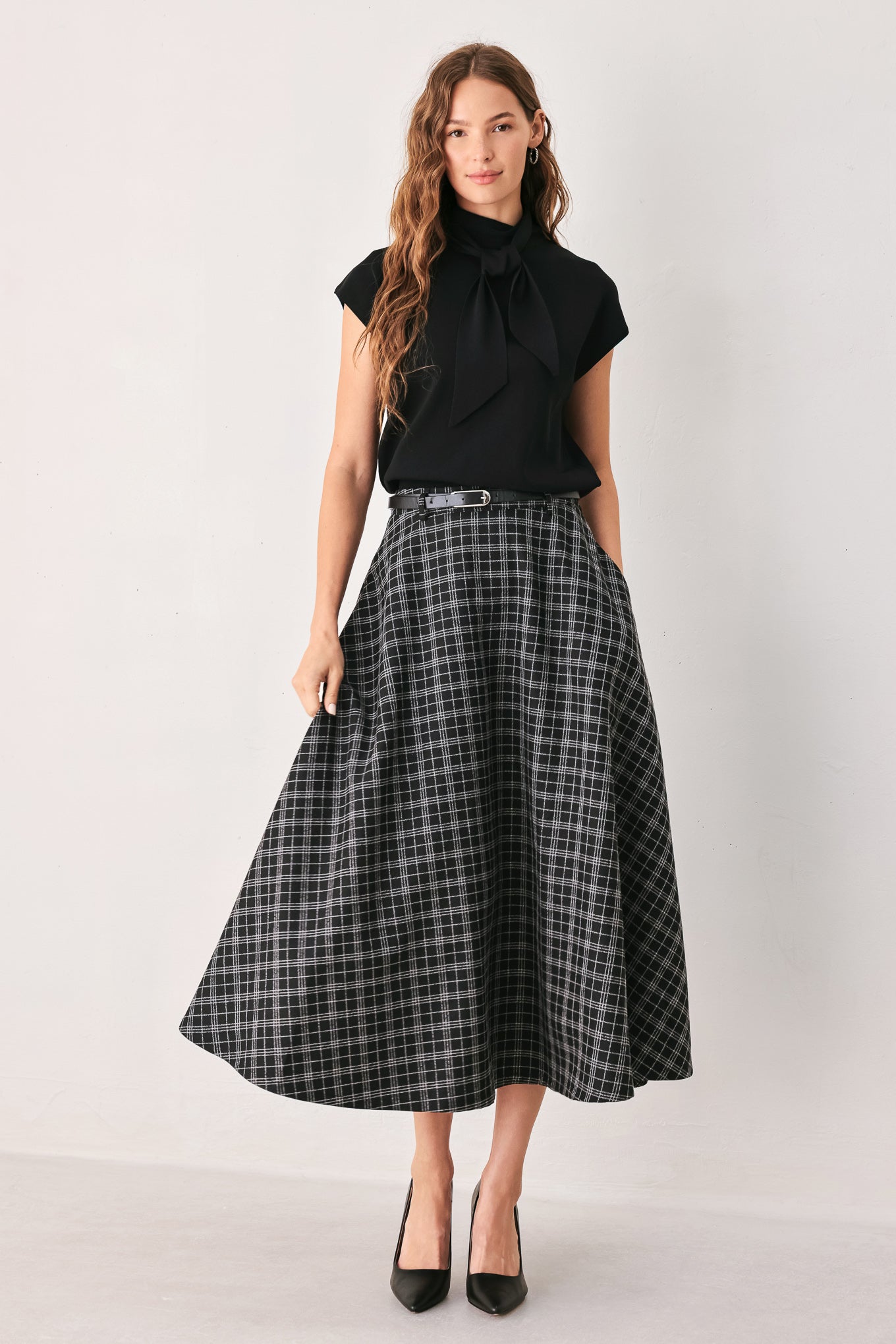 A woman wearing a black and gray plaid midi skirt with a black belt | FREEMARKET