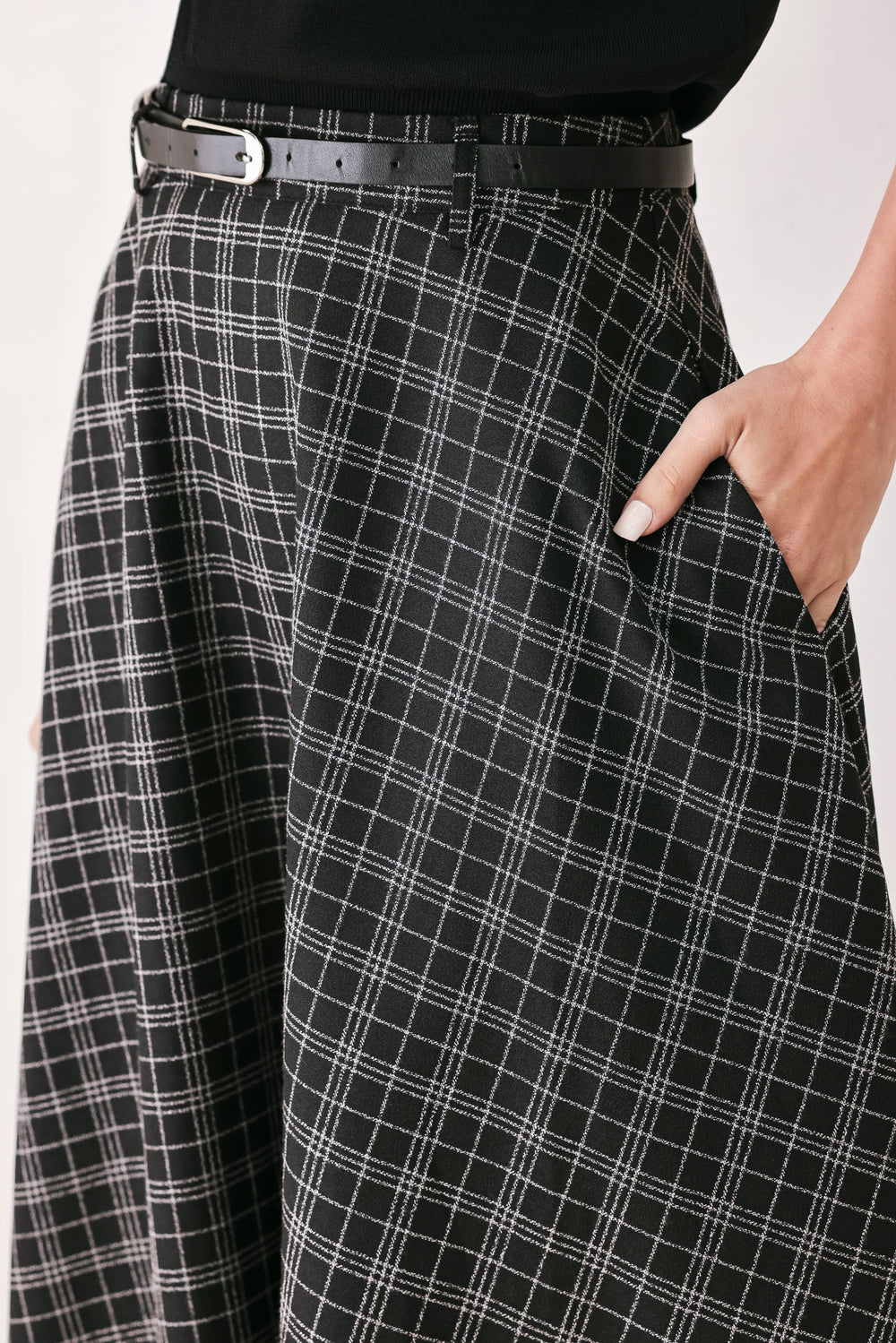 A woman wearing a black and gray plaid midi skirt with a black belt | FREEMARKET